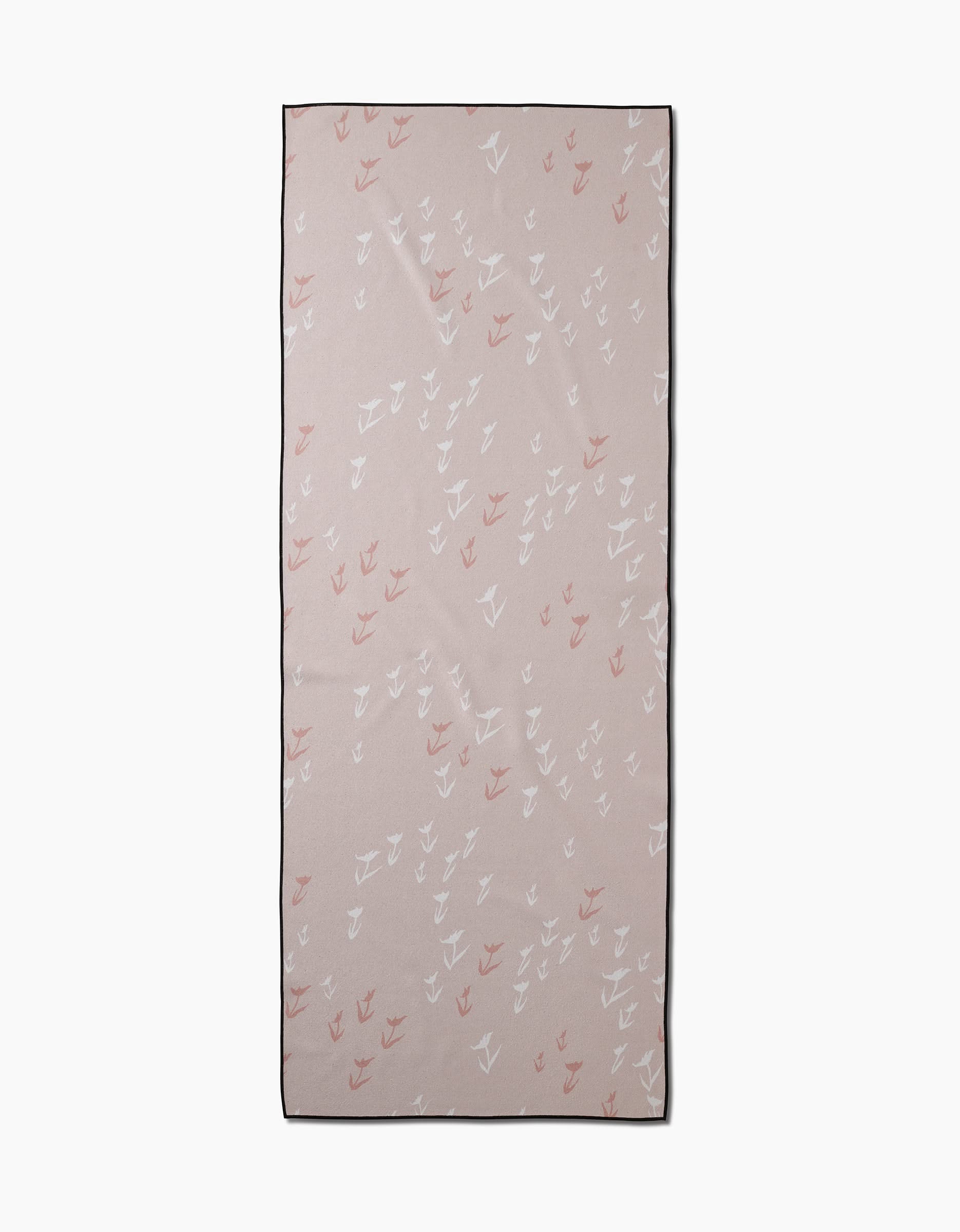The You Grow Girl yoga towel by Aubrey Fairchild is a rectangular, light beige towel made from recycled materials, featuring white and pink bird silhouettes and a thin black border, displayed flat on a plain white background.