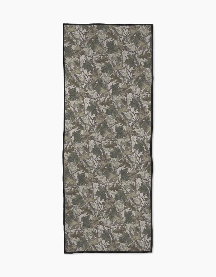 The Geometry Dad Camo yoga towel features a green and brown camouflage pattern with a thin black border, laid flat on a white background. Made from recycled materials, it blends style and sustainability for your yoga practice.
