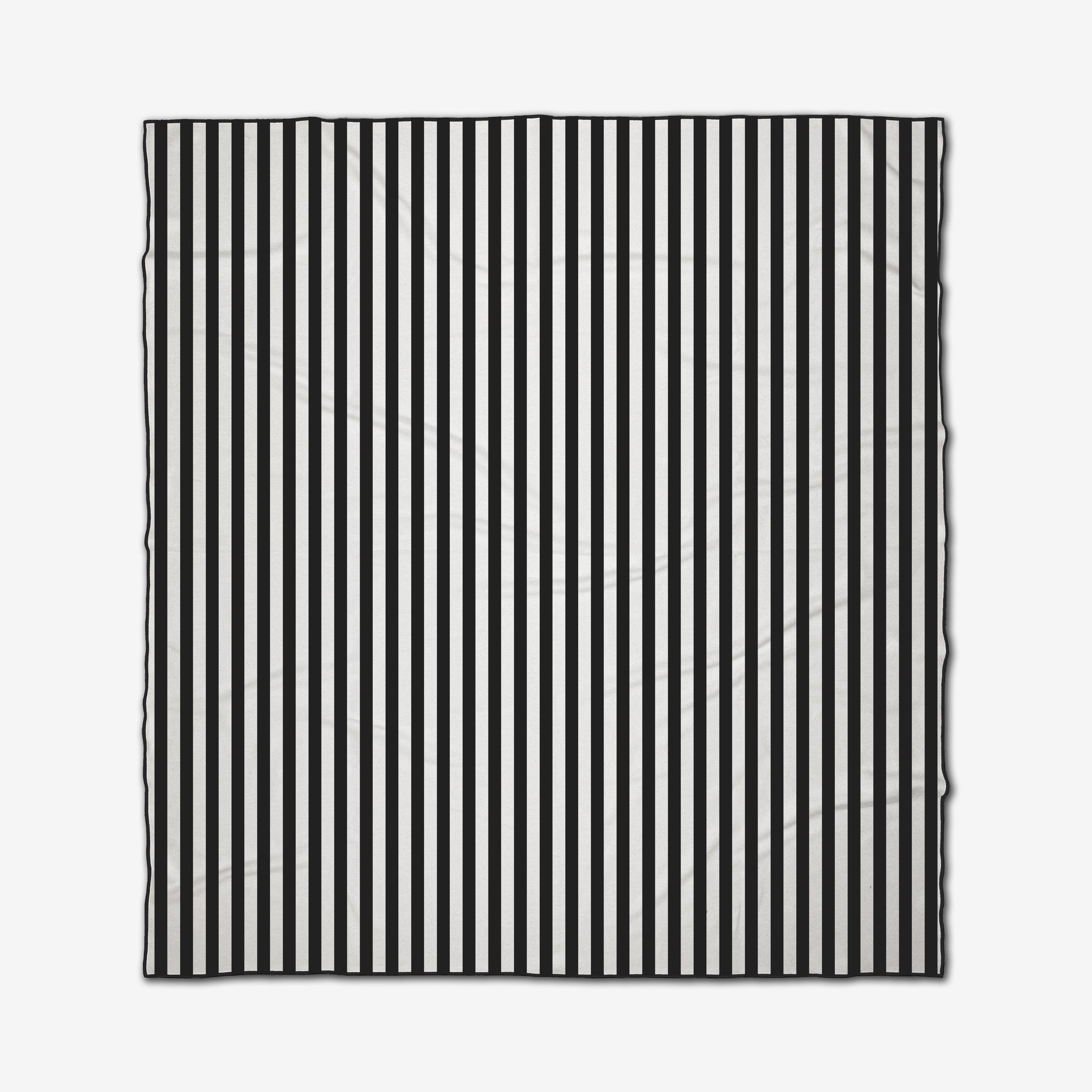 The GEOMETRY Black Stripes is a square recycled beach blanket with evenly spaced vertical black and white stripes, slightly wrinkled and shown against a white background.