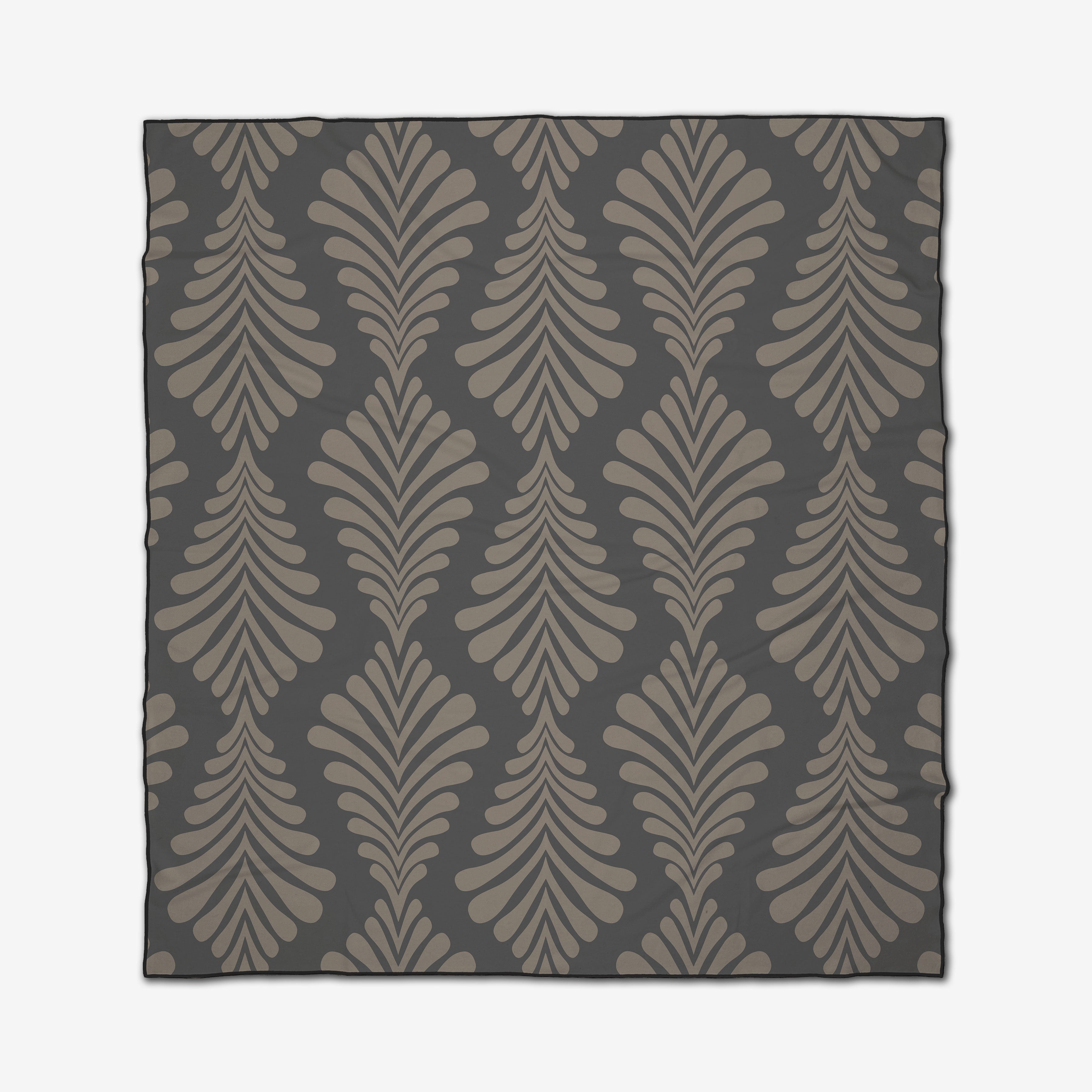 The GEOMETRY Dark Neutrals is a quick-drying beach blanket with a repeating pattern of stylized curved leaf shapes in taupe and beige on a dark gray background.