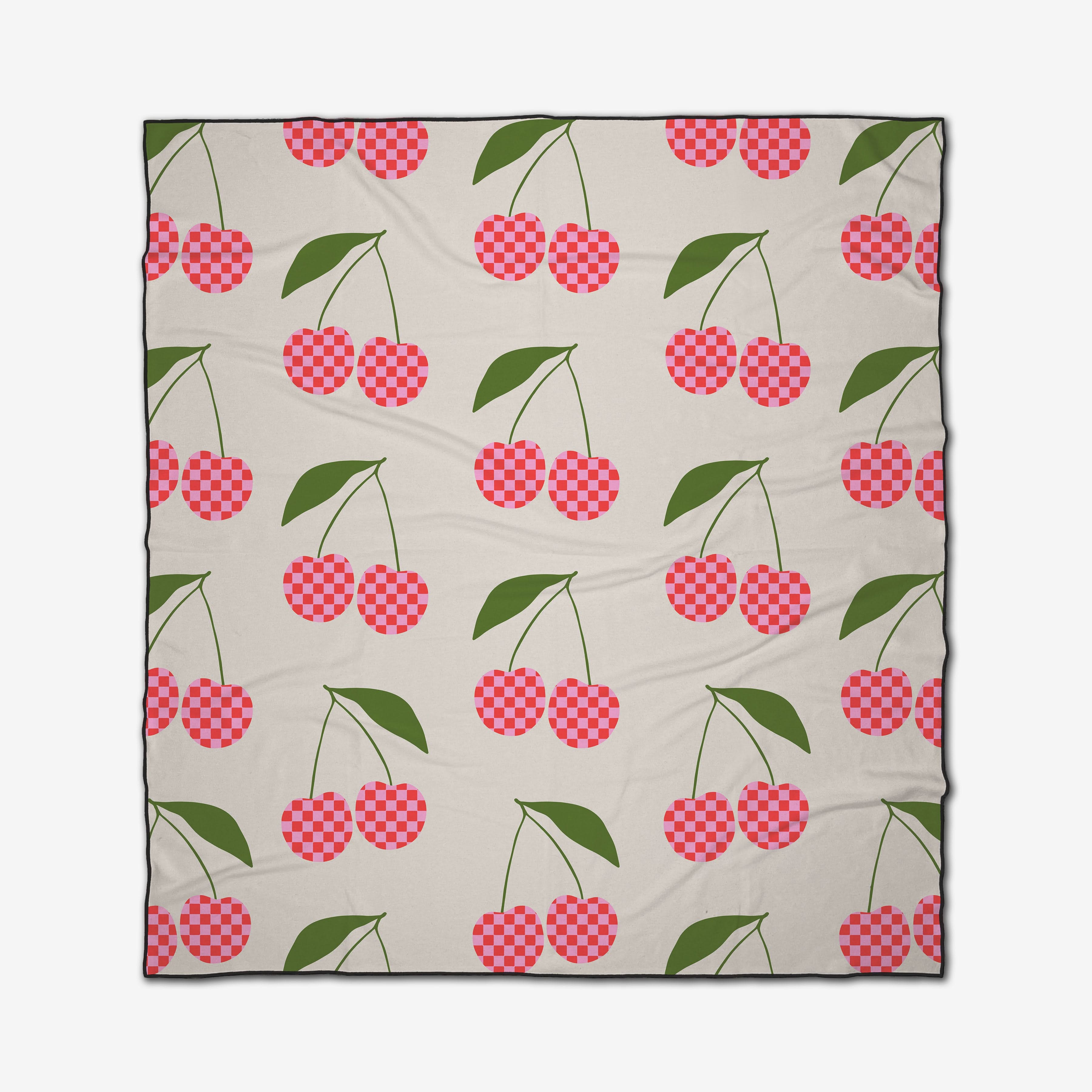 GEOMETRY’s Disco Cherry is a quick-drying beach blanket with red and pink checkered cherries and green leaves on a light beige background.