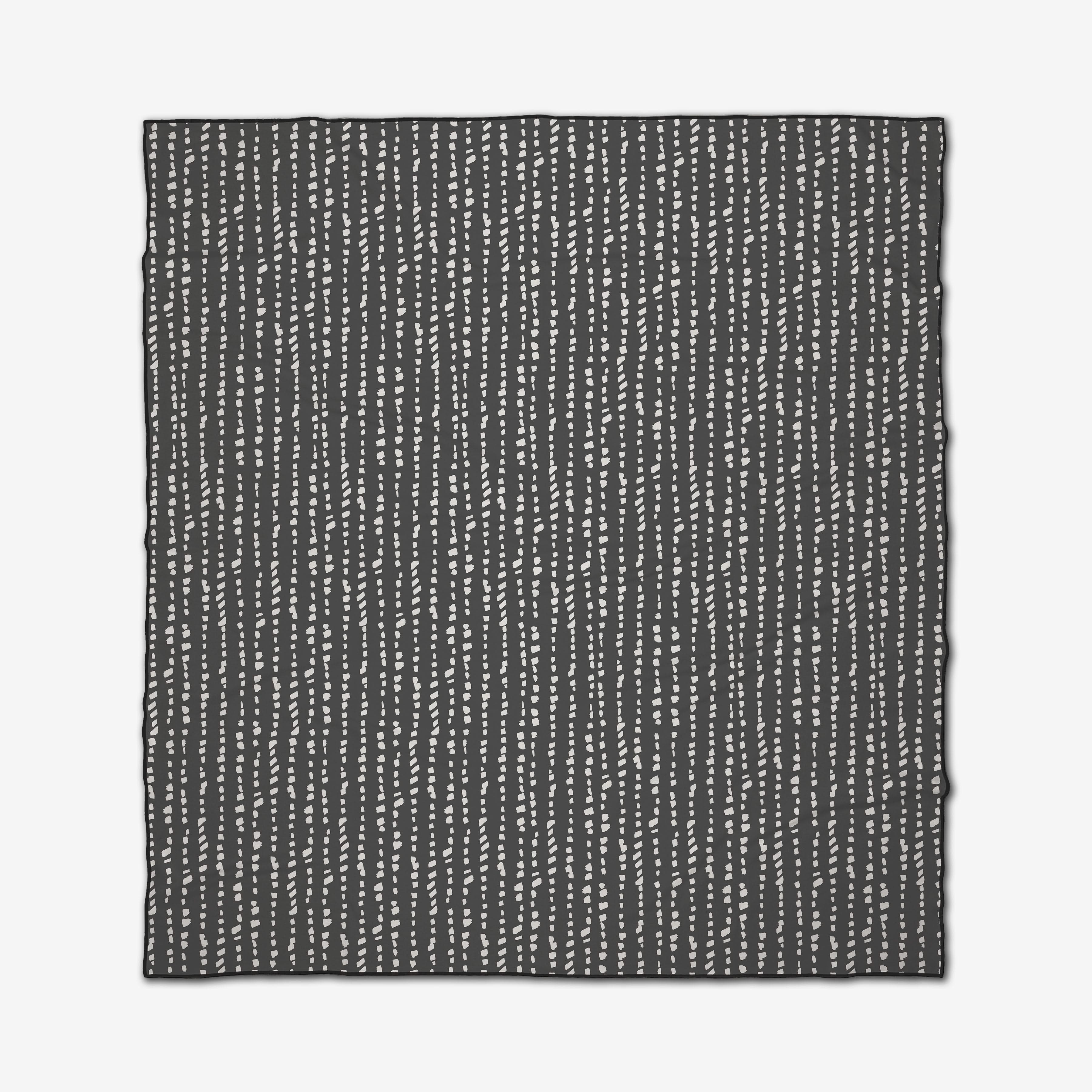The GEOMETRY Little Prints beach blanket features a black rectangular design with evenly spaced vertical rows of small white dots for a minimalist look. Quick-drying and neatly finished edges add to its modern appeal.