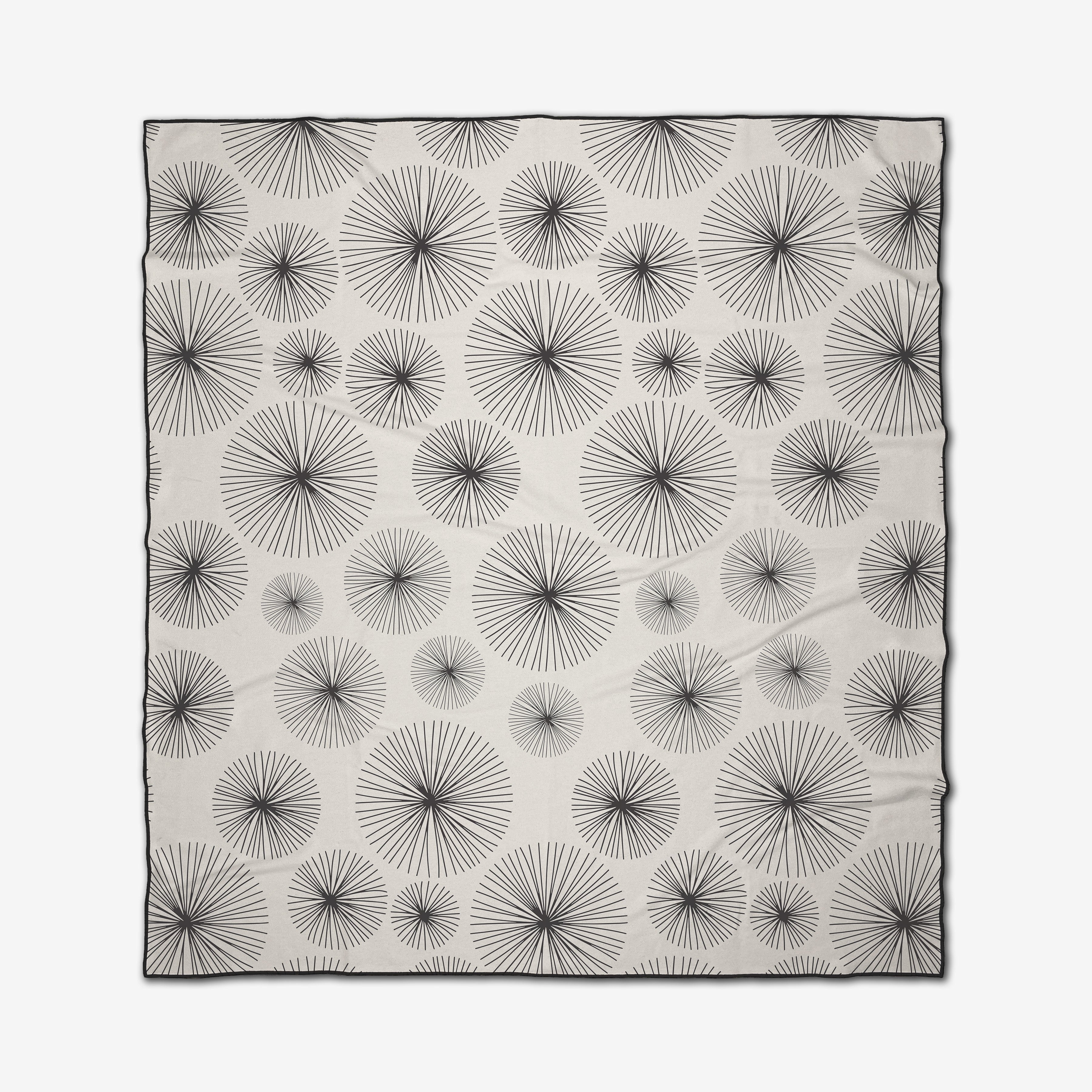 The GEOMETRY Sky Party is a rectangular white micro-loop beach blanket with evenly spaced black radial starburst patterns of varying sizes and a thin black border.