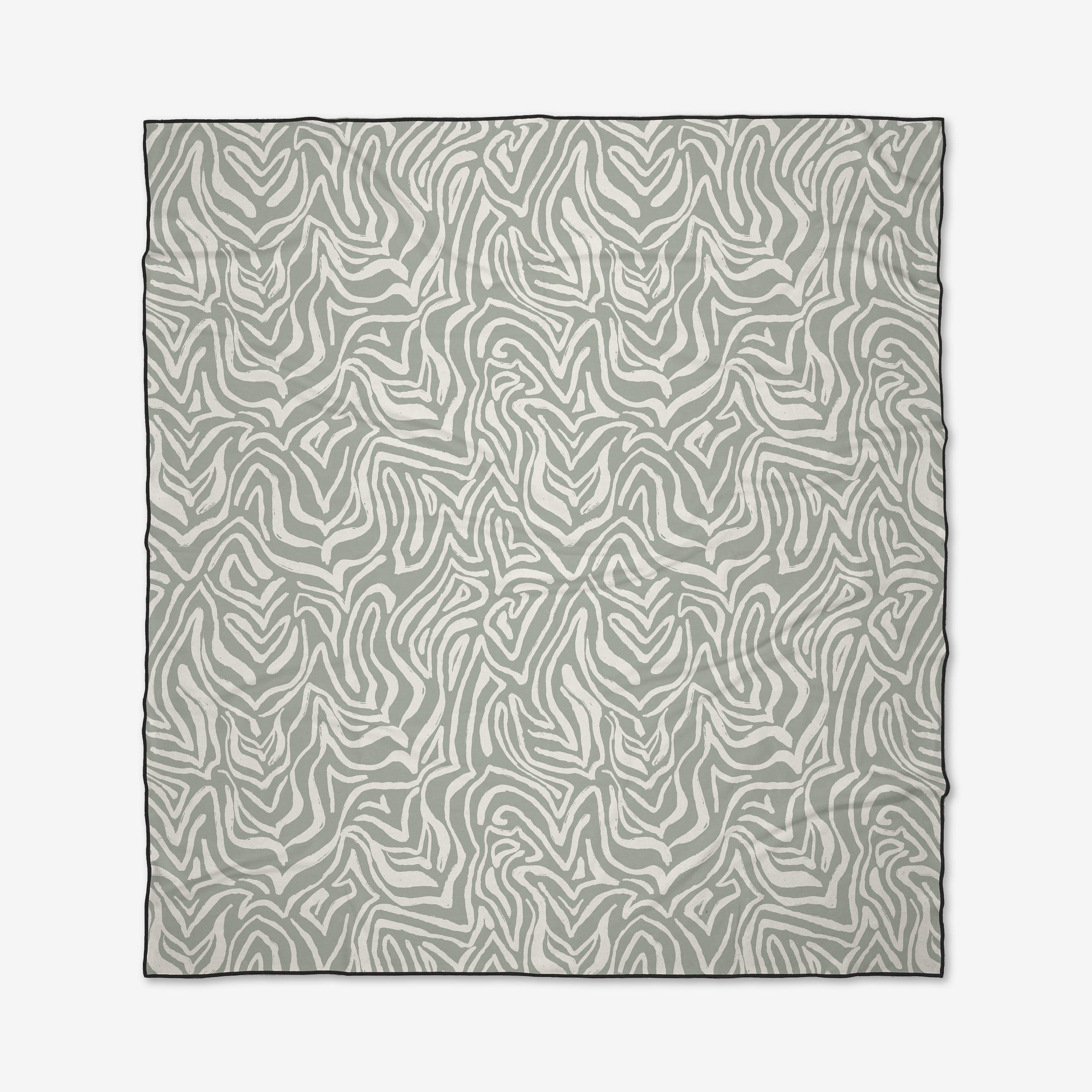 The Wild Marks beach blanket by Hufton Studio features a gray and white abstract zebra stripe pattern with wavy, irregular lines for an organic look. Black borders finish the design.