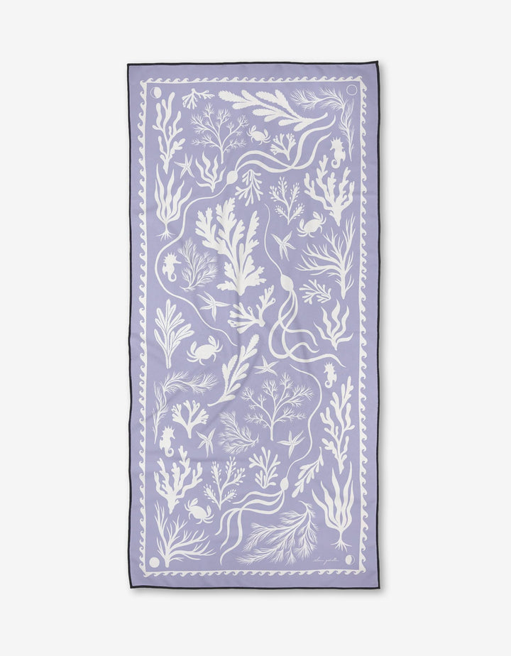Elana Gabrielles Coastal Tides is a rectangular lavender micro-loop beach towel with white seaweed, coral, fish, crab, and seashell illustrations plus a decorative border. Quick-drying—ideal for the shore.