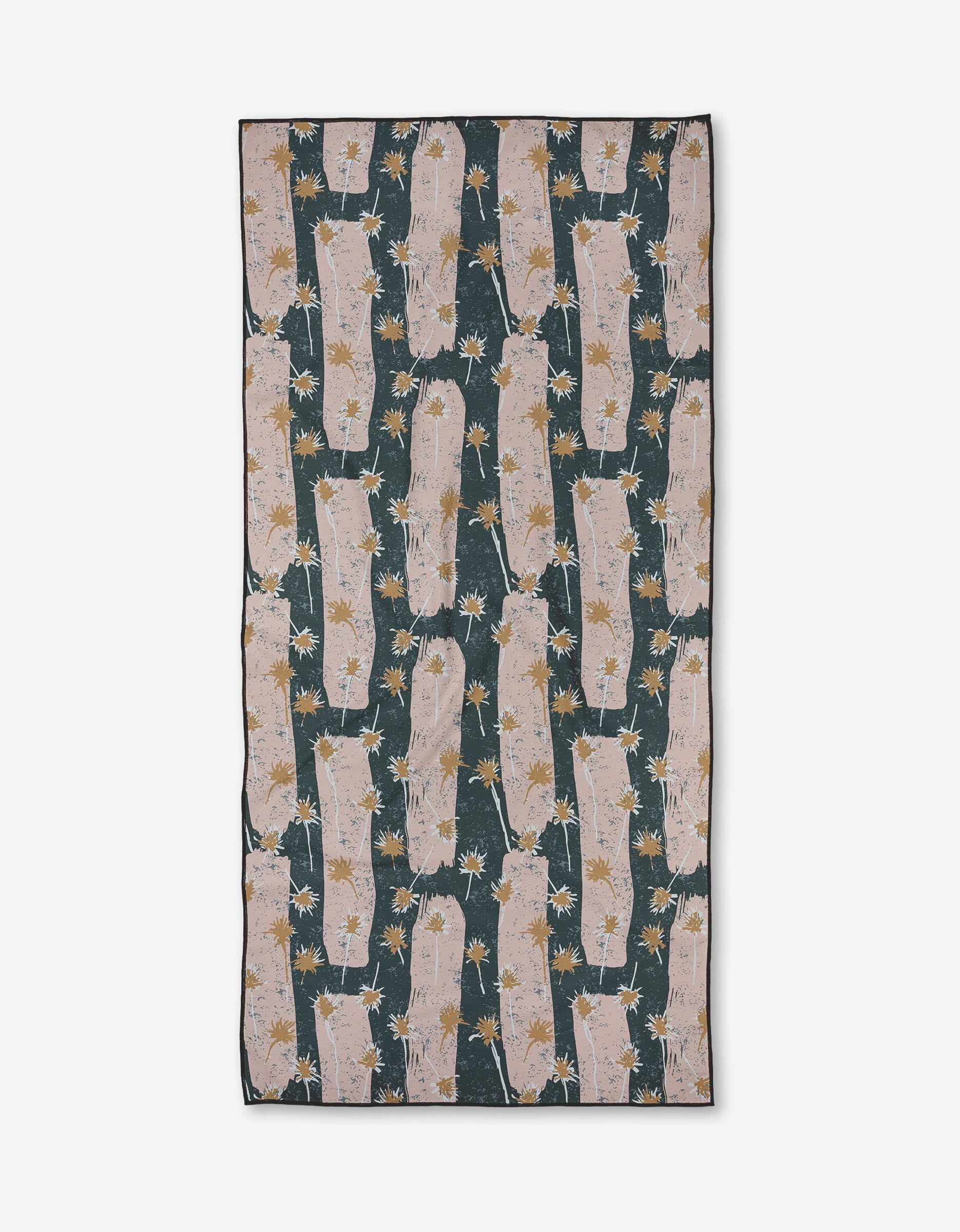 The Toboggan Avenue Coastal is a rectangular recycled beach towel with pink llamas and white and yellow flowers in a repeating pattern on dark green, finished with black-edged borders.