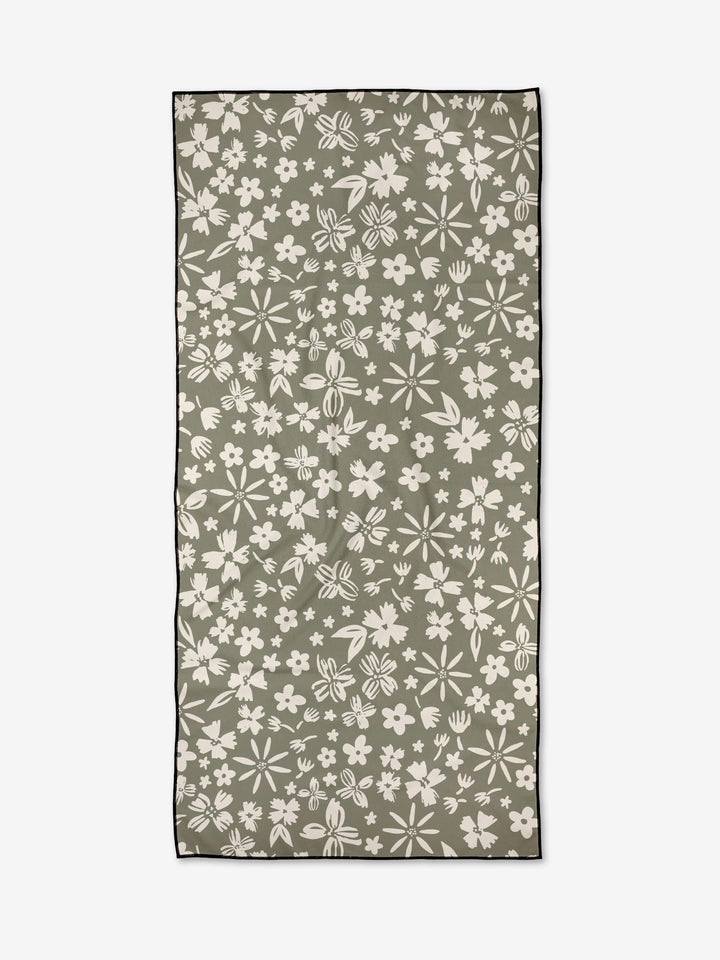 The Flourish Gardens towel by Hufton Studio is a rectangular, olive-green, quick-drying piece featuring a white floral pattern with various sized flowers and leaves, and finished with a thin black border around the edges.