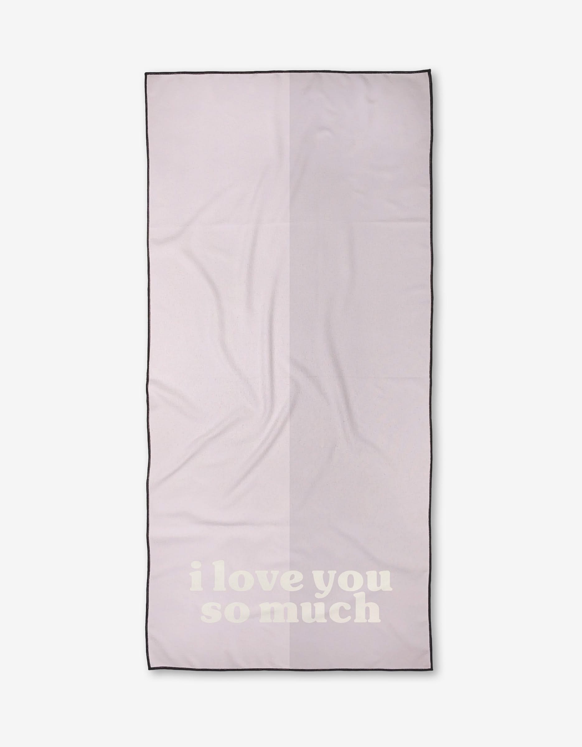 A light pink rectangular Kelsi Fullmer ilysm Micro-loop Beach Towel with black trim and i love you so much in large white letters near the bottom.