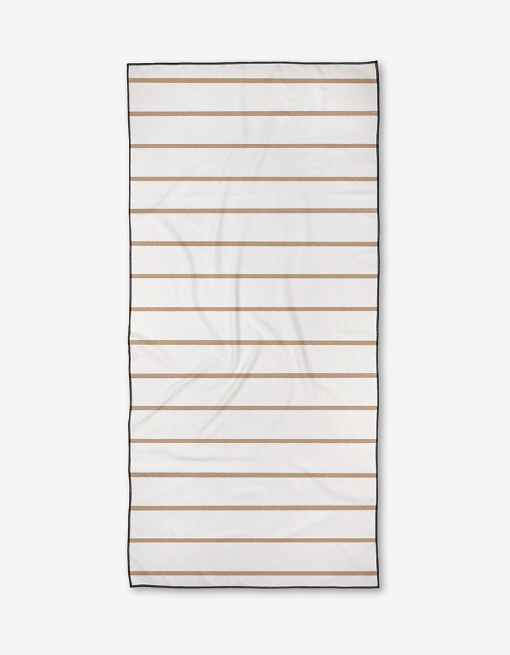 The Kailee Wright Juel towel is a rectangular white beach towel with horizontal beige stripes and a thin black border, laid flat on a white background. Made from quick-drying, post-consumer recycled materials.