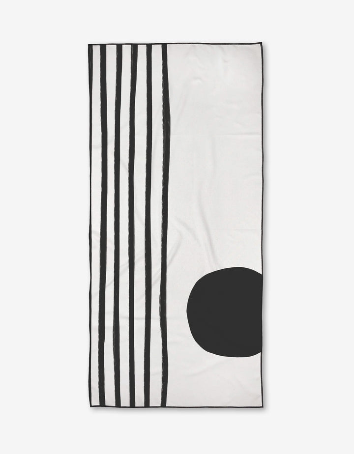 The Laurz beach towel by Kailee Wright is rectangular, white, and features five vertical black lines on the left side with a large solid black oval at the lower right.