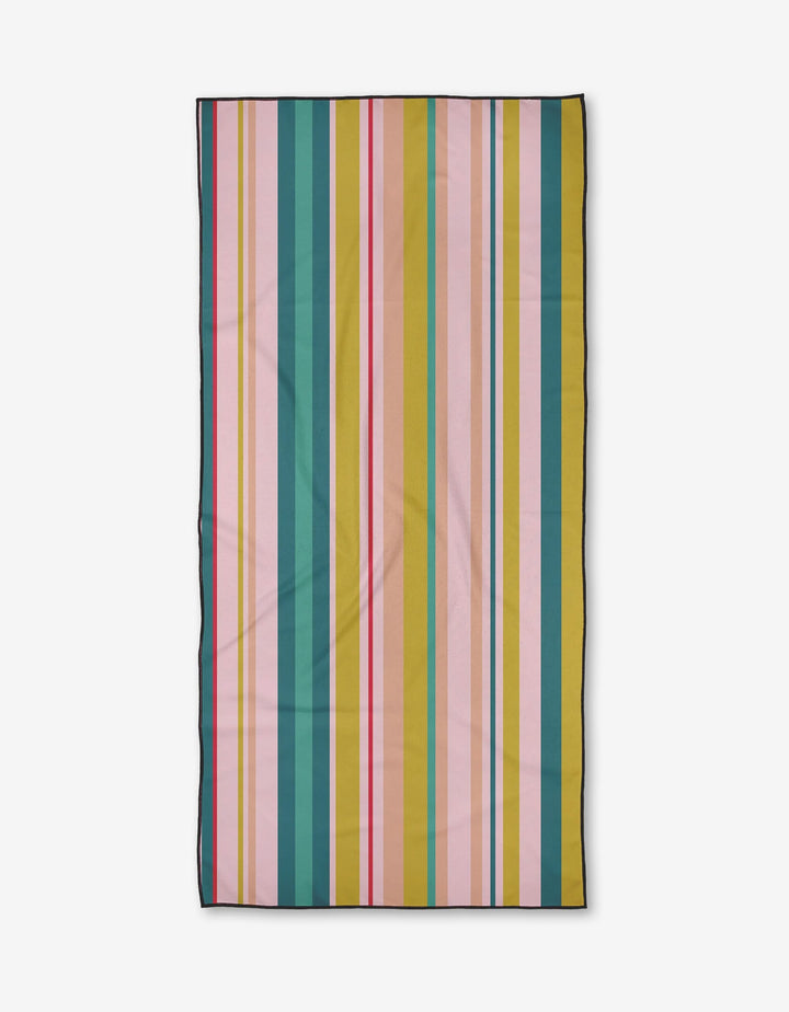 The GEOMETRY Line It Up Retro Beach Towel features quick-drying, post-consumer recycled materials and a rectangular design with vibrant vertical stripes in pink, green, blue, yellow, orange, and red on white with a black border.