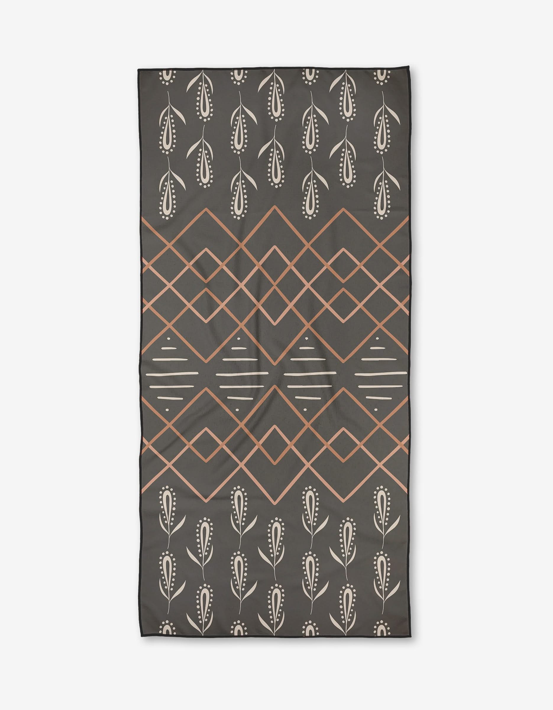The Amita Nair Night Mist is a quick-drying beach towel with a rectangular black design, orange diamond geometry, white lines, and rows of white stylized leaf motifs on the top and bottom.
