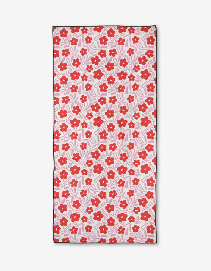 The Pink Wild Garden beach towel by Happy Hemera features red flowers and pink leaves on white. Made from quick-drying, recycled materials, it’s finished with a thin black border for a stylish touch.