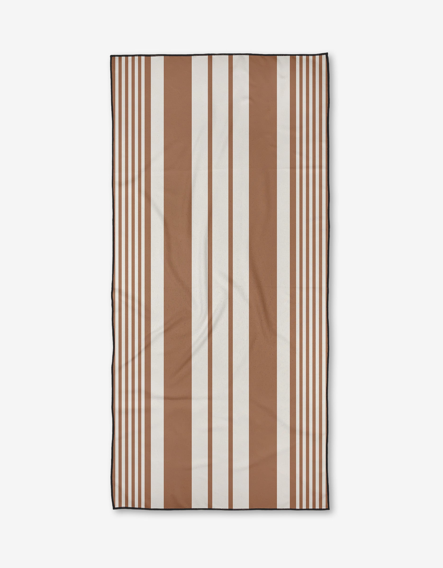 The Reina beach towel by Becki Owens features alternating wide and narrow vertical stripes in brown and white on a plain background, and is crafted from quick-drying recycled materials.