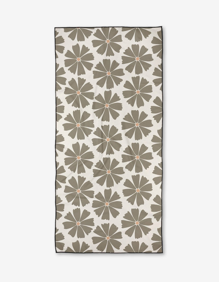 The Hufton Studio Retro Daisy is a rectangular beach towel made from recycled materials, featuring large olive green flowers with orange centers on an off-white background, a thin dark border, and soft micro-loop texture.
