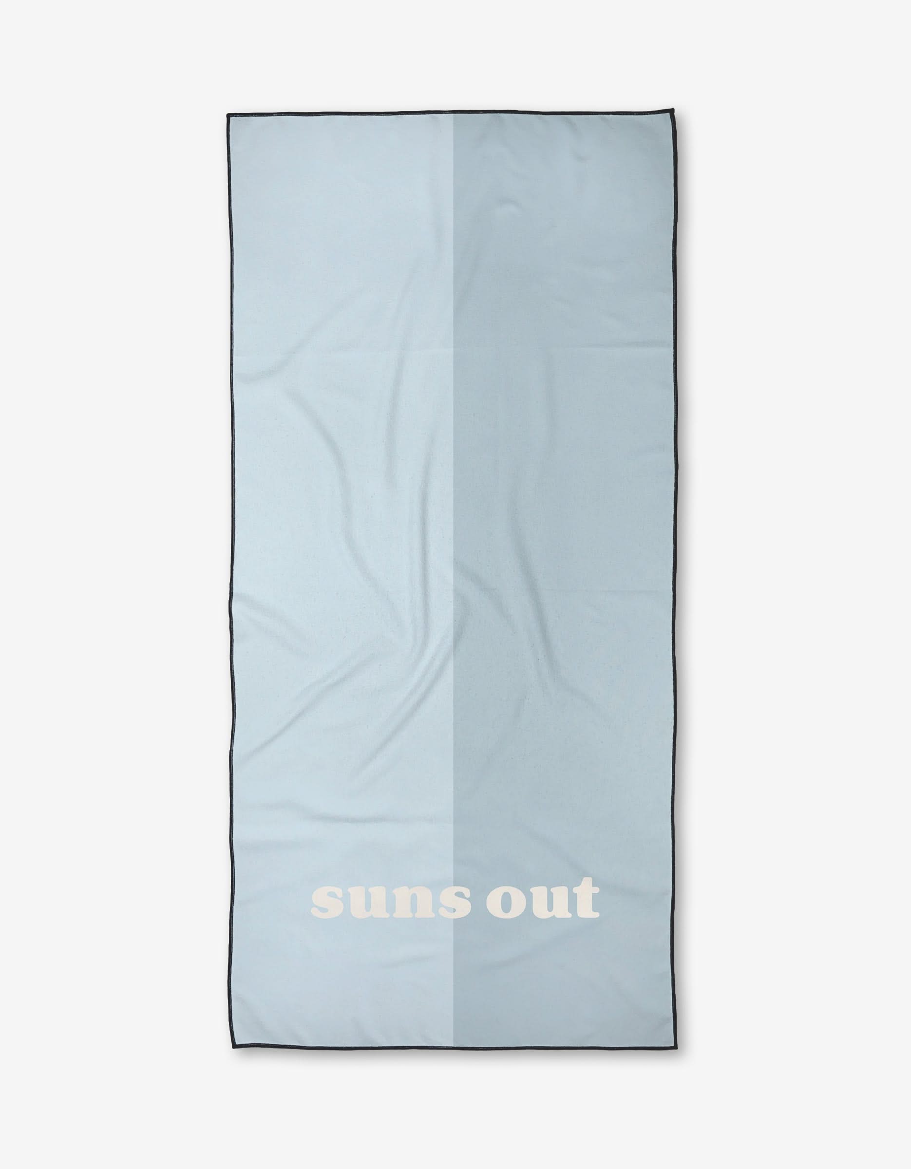 A light blue rectangular beach towel by Kelsi Fullmer, named Suns Out, features bold white suns out text near one end and is shown against a plain white background.