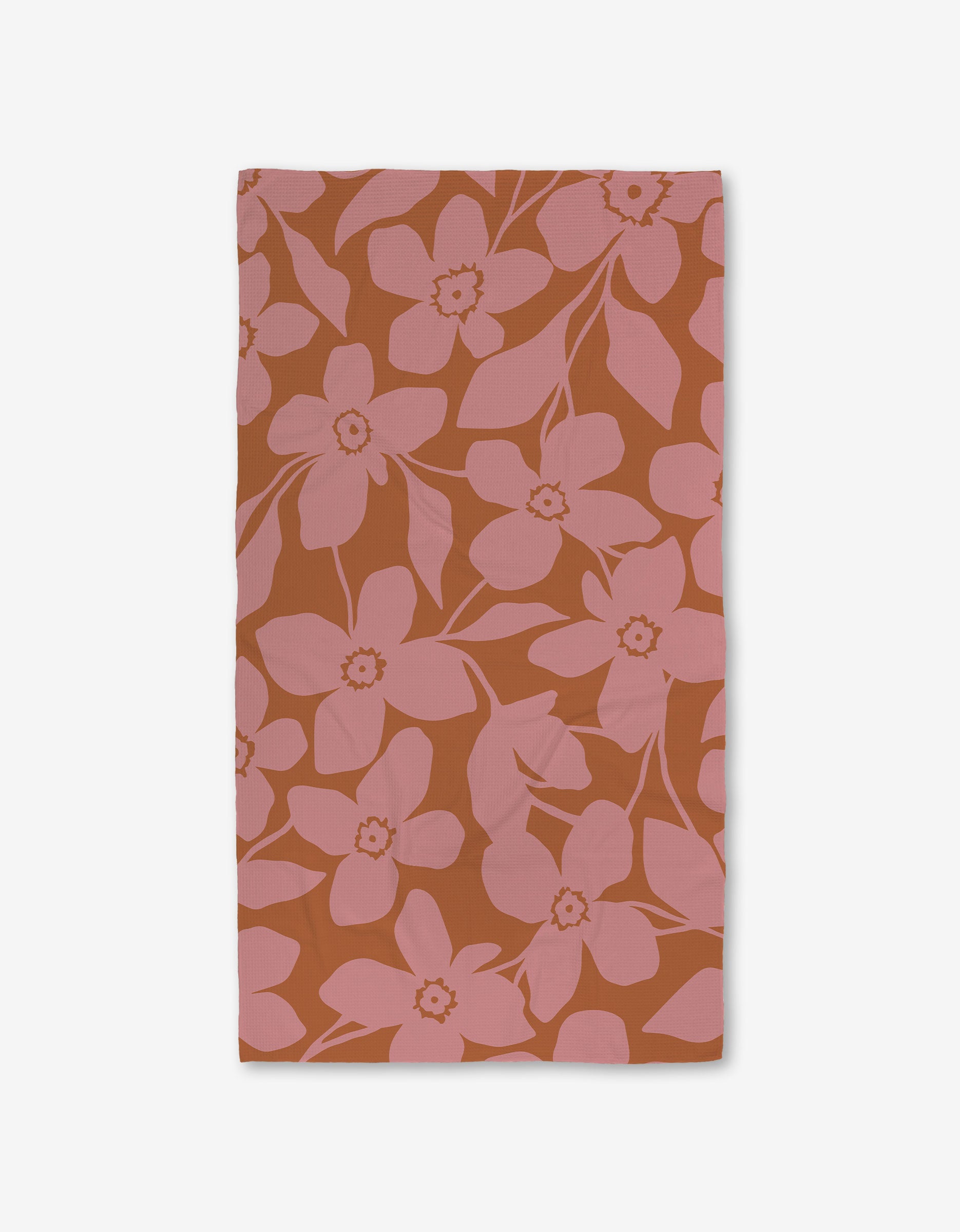 The GEOMETRY Big Fuchsia Flowers rectangular cloth napkin showcases large pink blossoms and leaves on a burnt orange background, displayed flat on white, and crafted with ultra-absorbent Geoweave technology for enhanced function.