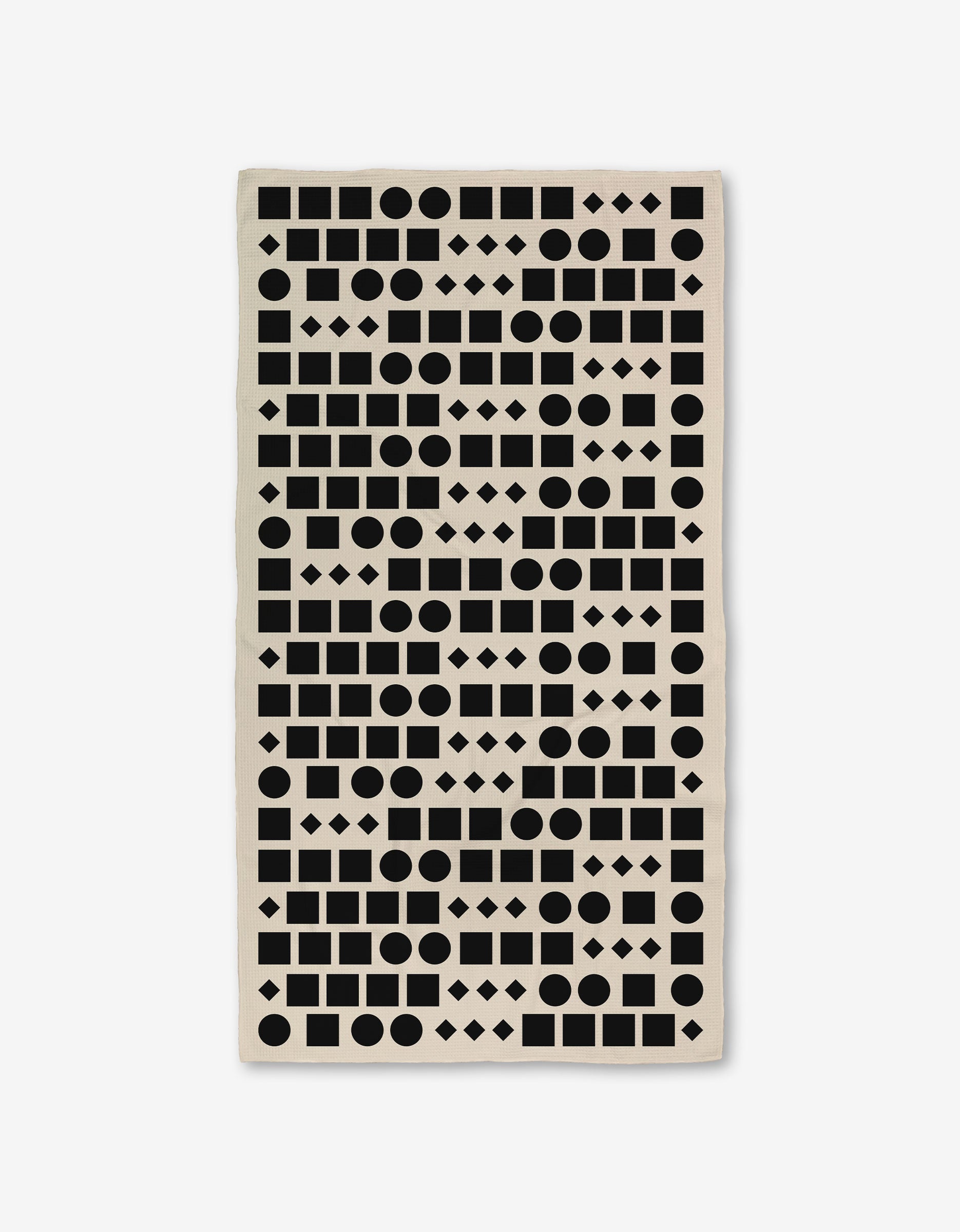 The GEOMETRY Coded bath towel is rectangular and beige, showcasing black geometric shapes—circles, squares, rectangles, and diamonds—in a repeating pattern on a white background. Made with ultra-absorbent Geoweave™ technology.