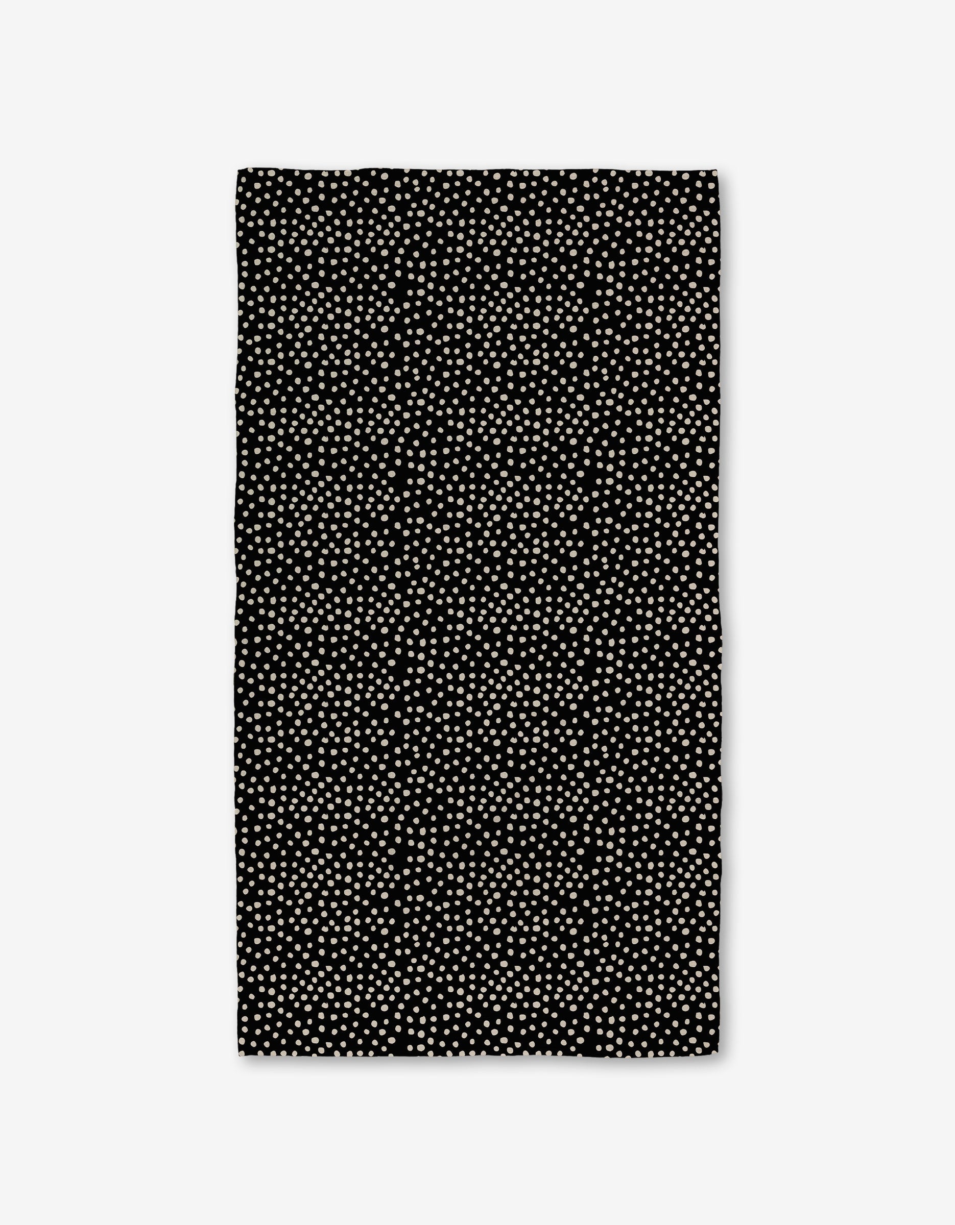 The Dotty Black Luxe Bath Towel by GEOMETRY showcases evenly spaced small white dots on a rectangular black surface, made with ultra-absorbent Geoweave technology, displayed against a white background.