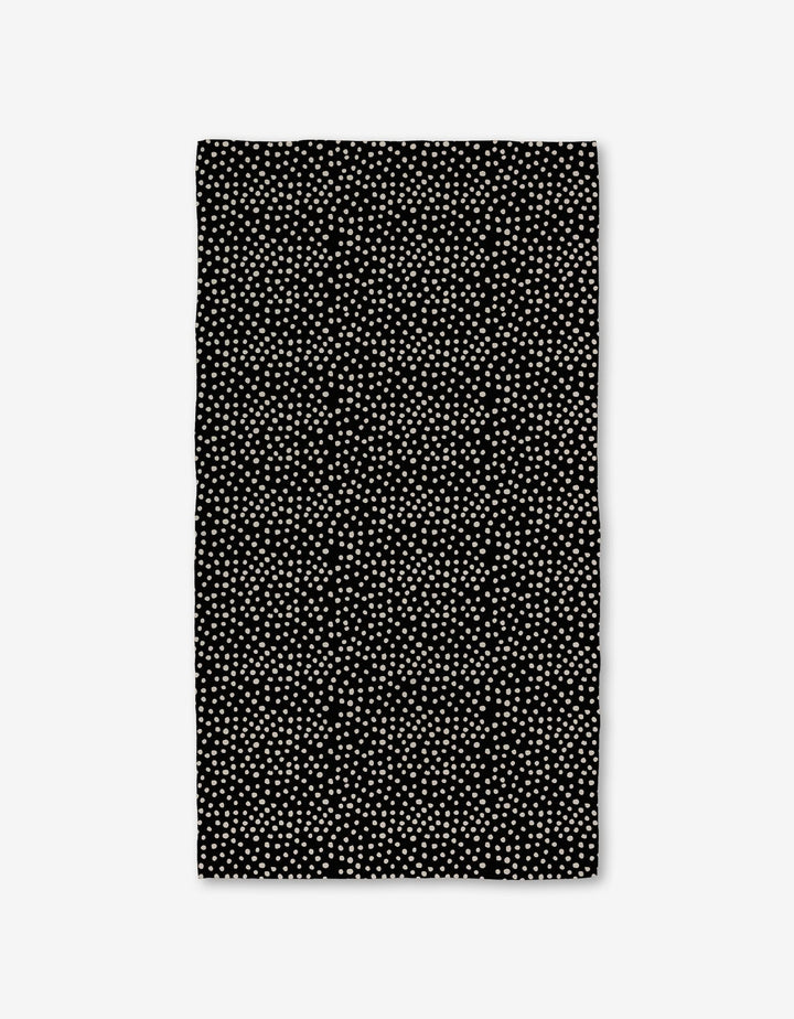 The Dotty Black Luxe Bath Towel by GEOMETRY showcases evenly spaced small white dots on a rectangular black surface, made with ultra-absorbent Geoweave technology, displayed against a white background.