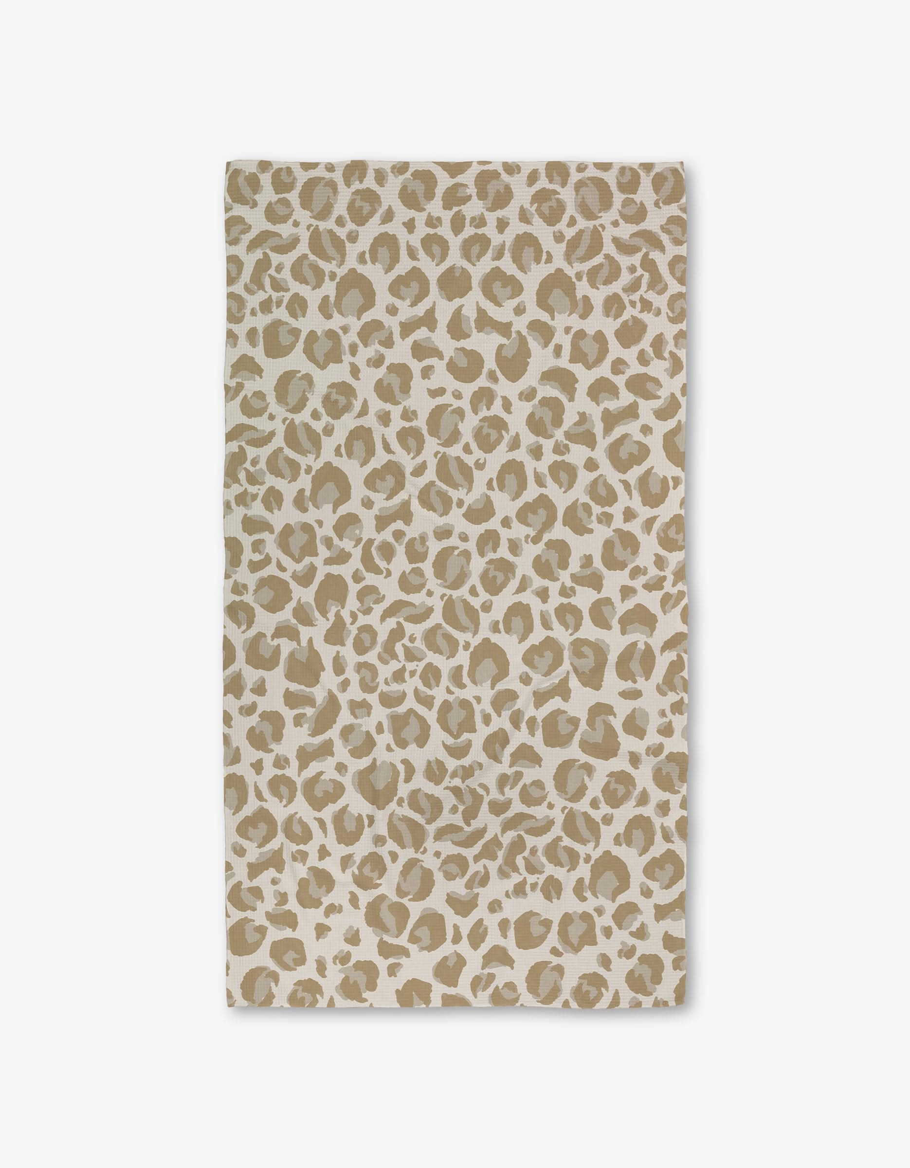 The GEOMETRY Light Leopard rug is a rectangular beige mat with a tan and white leopard print, set on a plain white background and crafted with ultra-absorbent Geoweave Technology for luxurious softness.