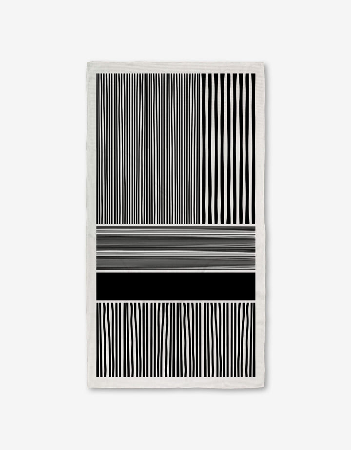 The Modern Form towel by GEOMETRY features Geoweave technology with black and white vertical stripes on the top and bottom, and abstract horizontal lines of varying thicknesses and shades in the middle for a modern look.
