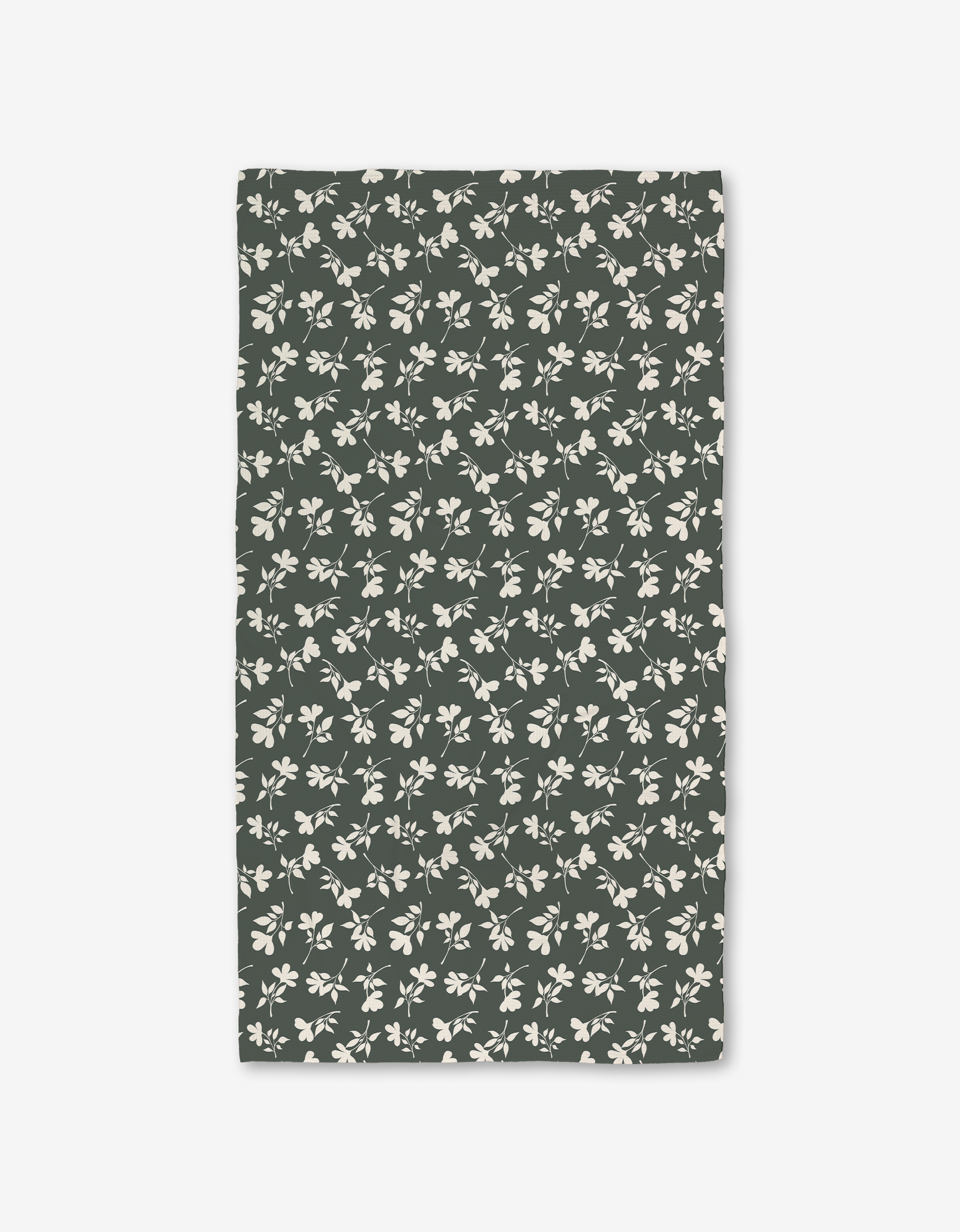 The Penelope napkin by Charlie Rowan Designs is a rectangular, dark green fabric napkin made from recycled materials and features a pattern of light beige leaves and branches.