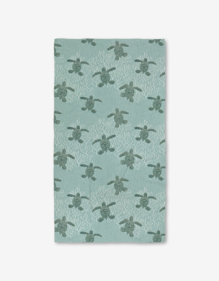 The Katie OShea Sea Turtles Luxe Bath Towel showcases sea turtles among white coral on a light teal background, made with Geoweave technology for an ultra-absorbent, premium feel.
