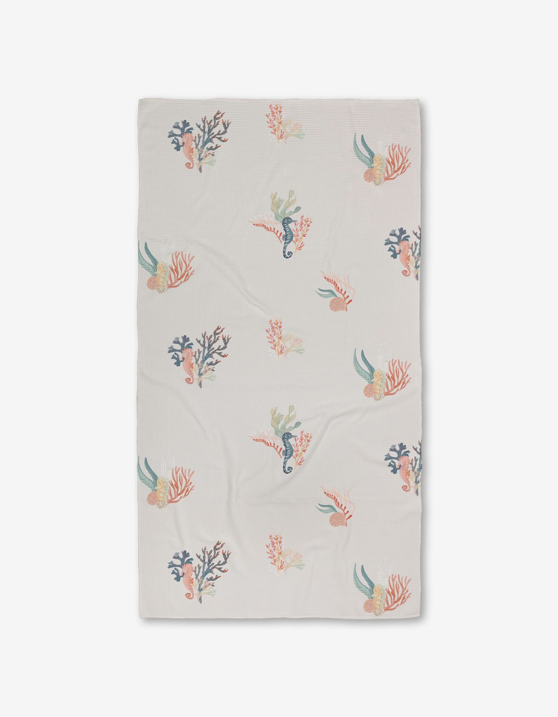 The Seahorse Serendipity Luxe Bath Towel by Janna Sue Design is a white, rectangular towel featuring colorful sea creatures, coral, and seaweed in blue, pink, orange, and green. Made with ultra-absorbent Geoweave technology. Shown flat on a white background.