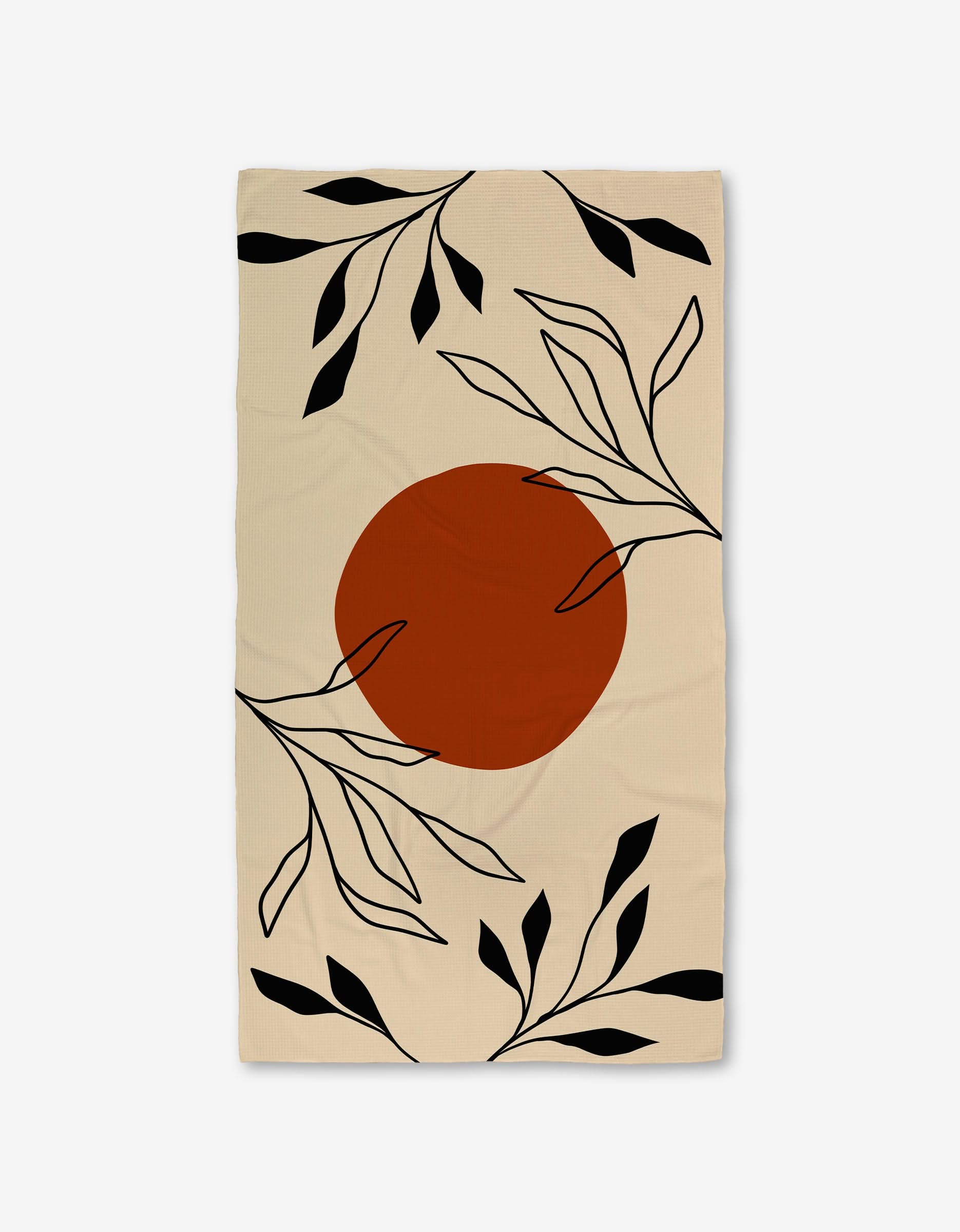 The GEOMETRY Sunset Bath is a beige rectangular Luxe Bath Towel featuring a large burnt orange circle in the center and black abstract leaf and branch designs, crafted with ultra-absorbent Geoweave technology.