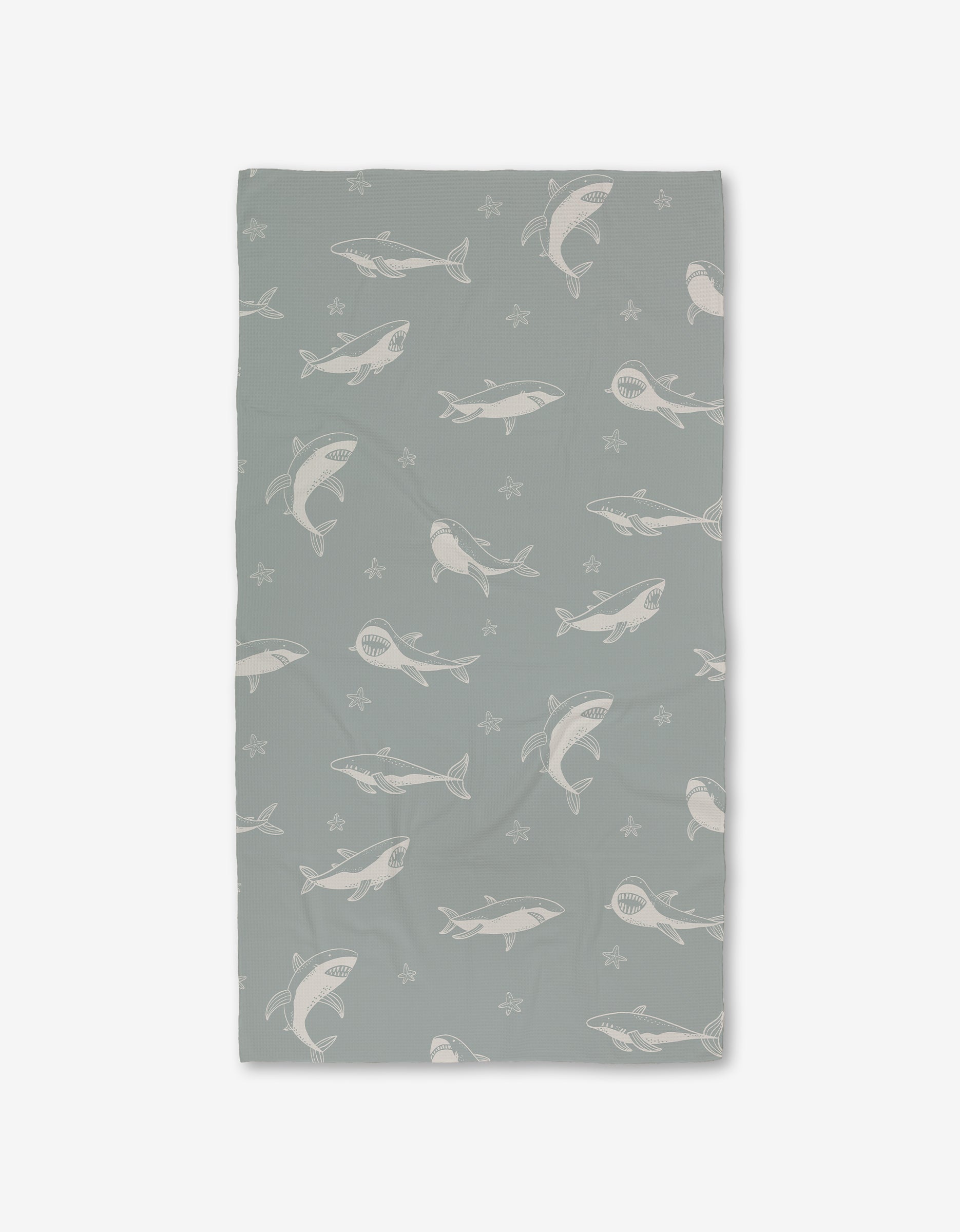 The Toothy Tales Luxe Bath Towel by Janna Sue Design features gray and white sharks with starfish on a light gray background. Made with Geoweave technology for exceptional softness and absorbency. Displayed against a plain white backdrop.