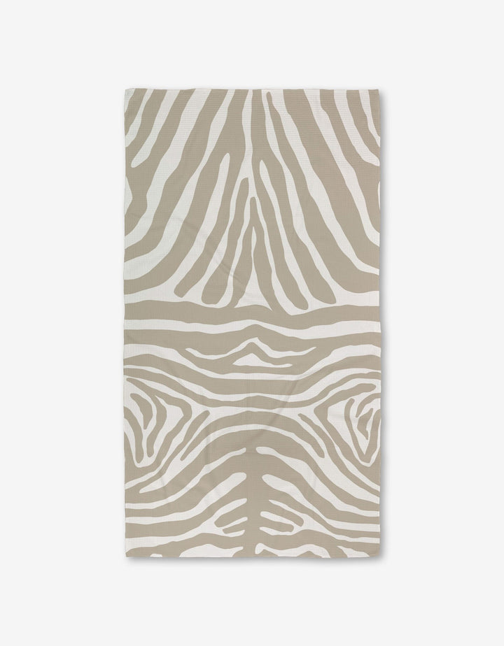 The GEOMETRY Zen Zebra bath towel, featuring a beige and white zebra stripe pattern and crafted with Geoweave technology for superior absorbency, is shown flat on a white background.