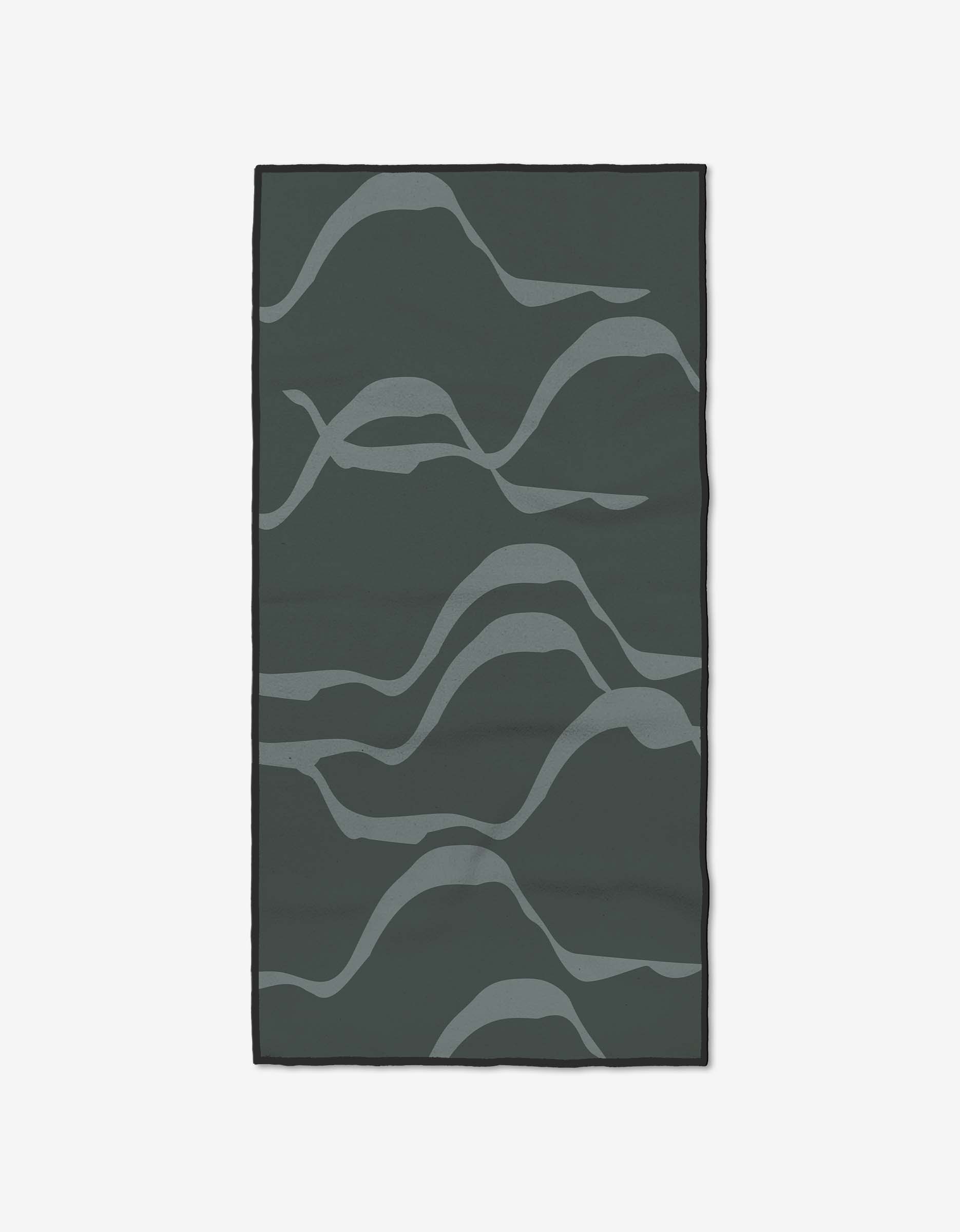 The Flow rug by GEOMETRY is a rectangular, dark green piece made from recycled materials, featuring abstract wavy light gray lines that create an organic pattern on its surface.
