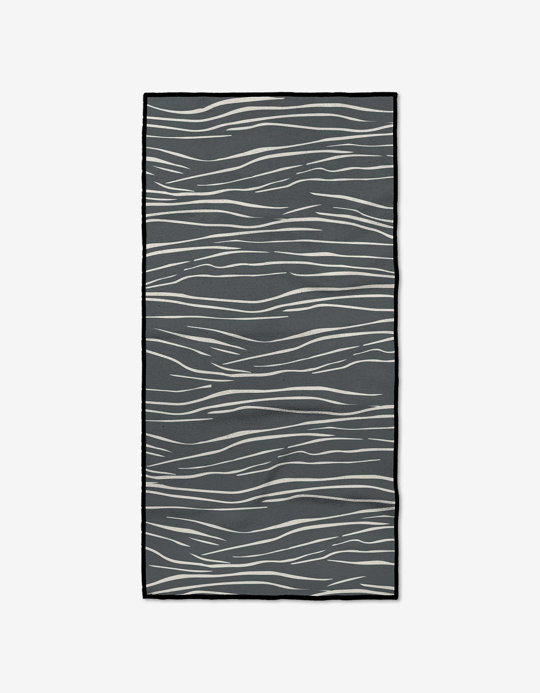 The GEOMETRY Flowing Midnight rug is rectangular and dark gray, with an abstract pattern of wavy white lines, made from recycled materials for a stylish, eco-friendly accent.