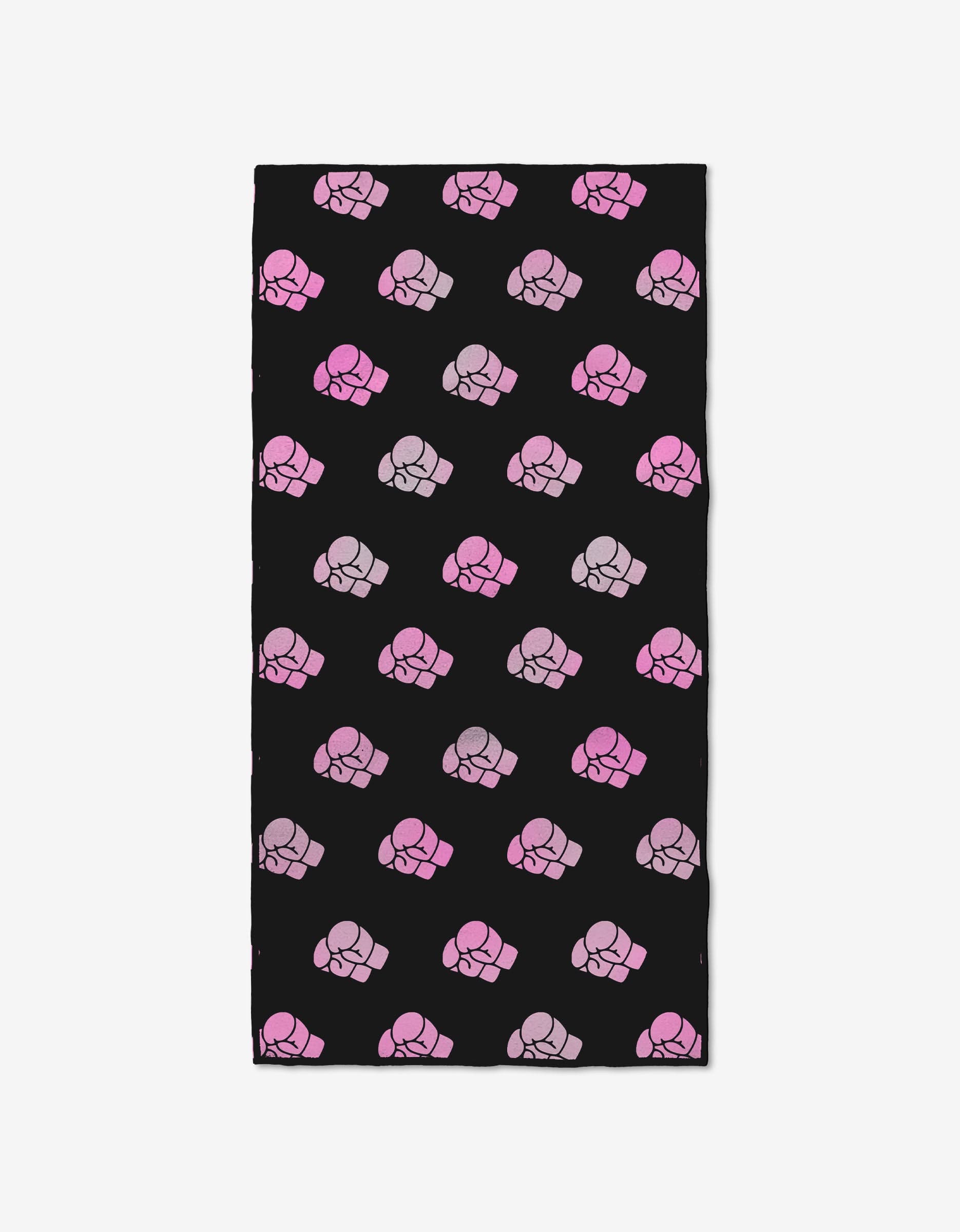 The Jab Cross Hook by Ashley Guarrasi is a rectangular black fitness towel made from ultra-absorbent recycled materials, featuring a diagonal pattern of raised fist icons in pink and purple shades.