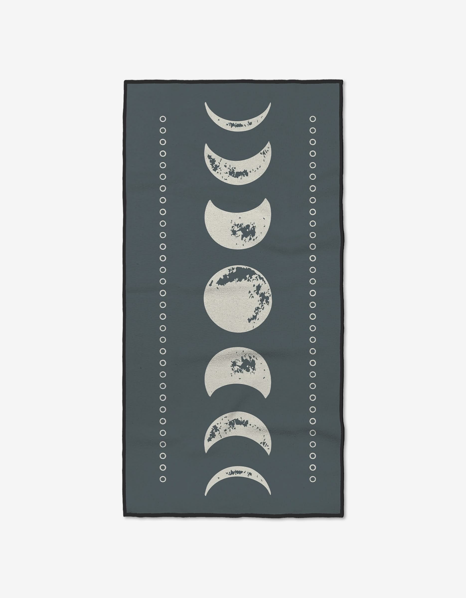 The Lunar Phases rug by Ashley Celena features ultra-absorbent Geoweave fabric, a dark blue background with the moon’s phases in a vertical line, and small white circles in parallel lines on both sides.