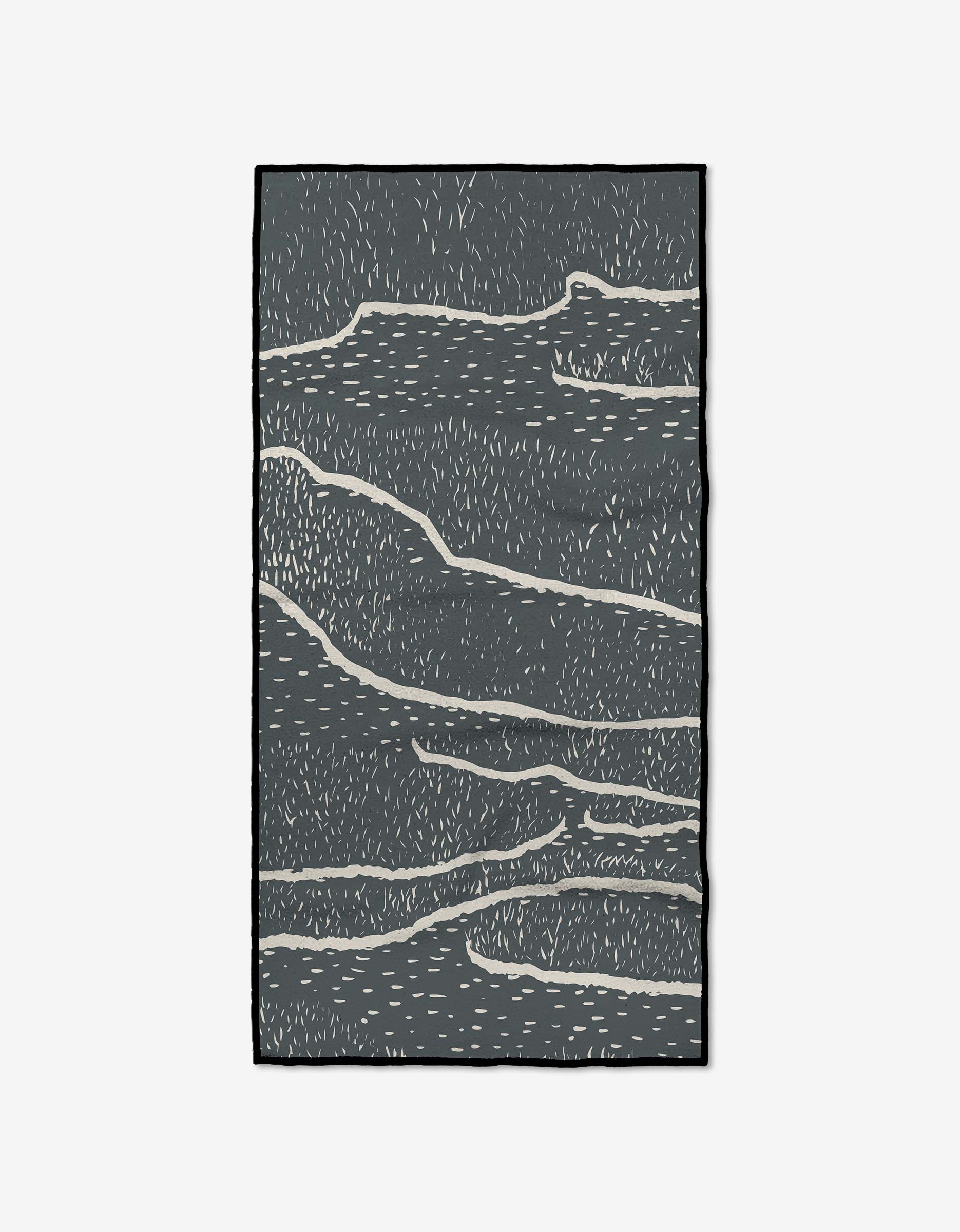 The GEOMETRY Wetlands Midnight rug features a rectangular shape with a dark gray base, abstract wavy white lines, and small dashes. Made from recycled materials, it has a minimalist look and is finished with a thin black border.