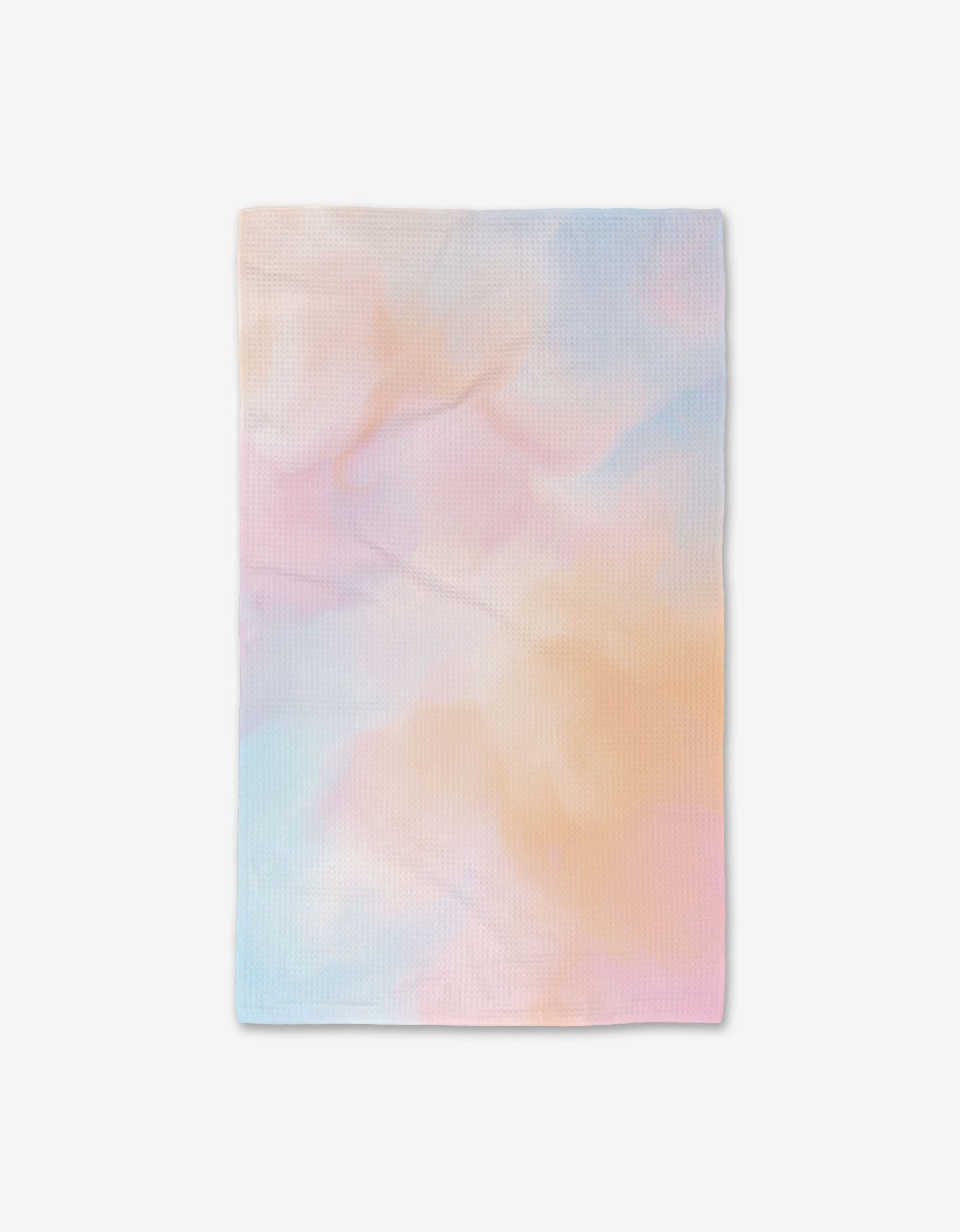 The GEOMETRY Cotton Candy Skies is a rectangular cloth crafted with Geoweave technology, featuring a soft watercolor pattern in blue, pink, and peach over a white background.