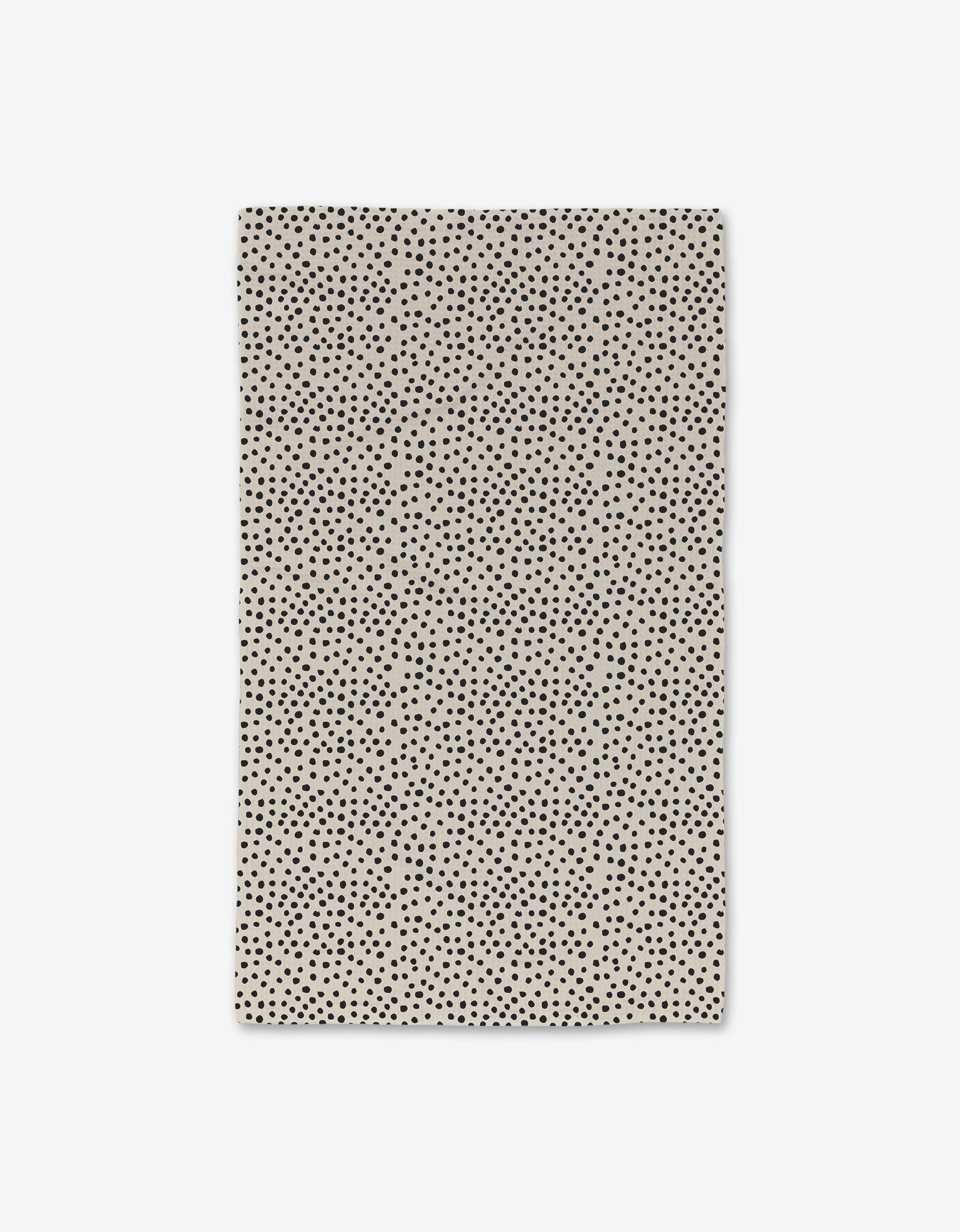 The GEOMETRY Dotty Tan Hand Towel features a rectangular beige design with an all-over pattern of small, irregular black polka dots. This ultra-absorbent towel combines elegance and practicality for everyday use. Displayed flat on a white background.