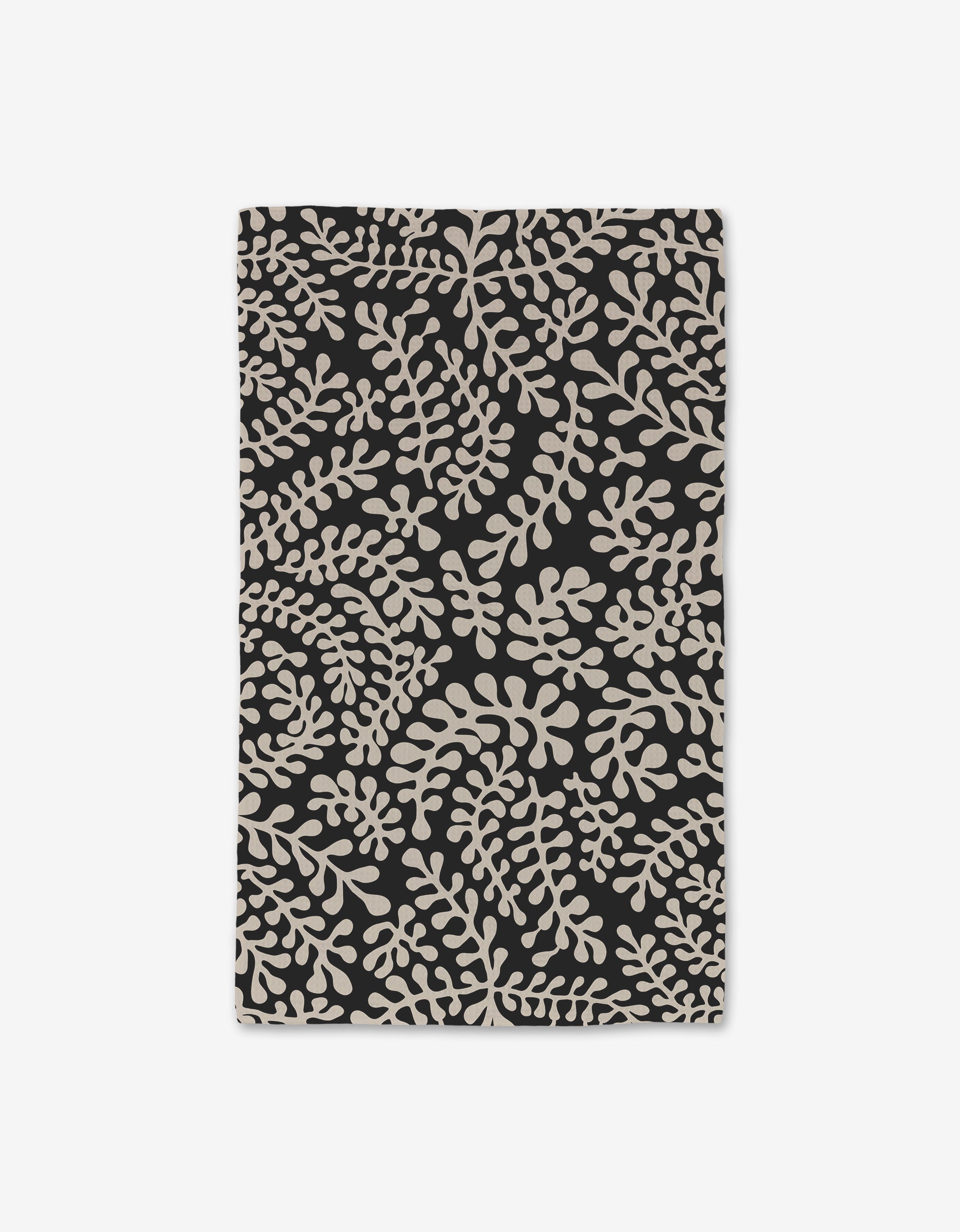 The Tangled hand towel by GEOMETRY features a black rectangular cloth with an abstract beige leafy pattern, crafted using Geoweave technology for ultra-absorbency—perfect as a luxe touch in any modern space.