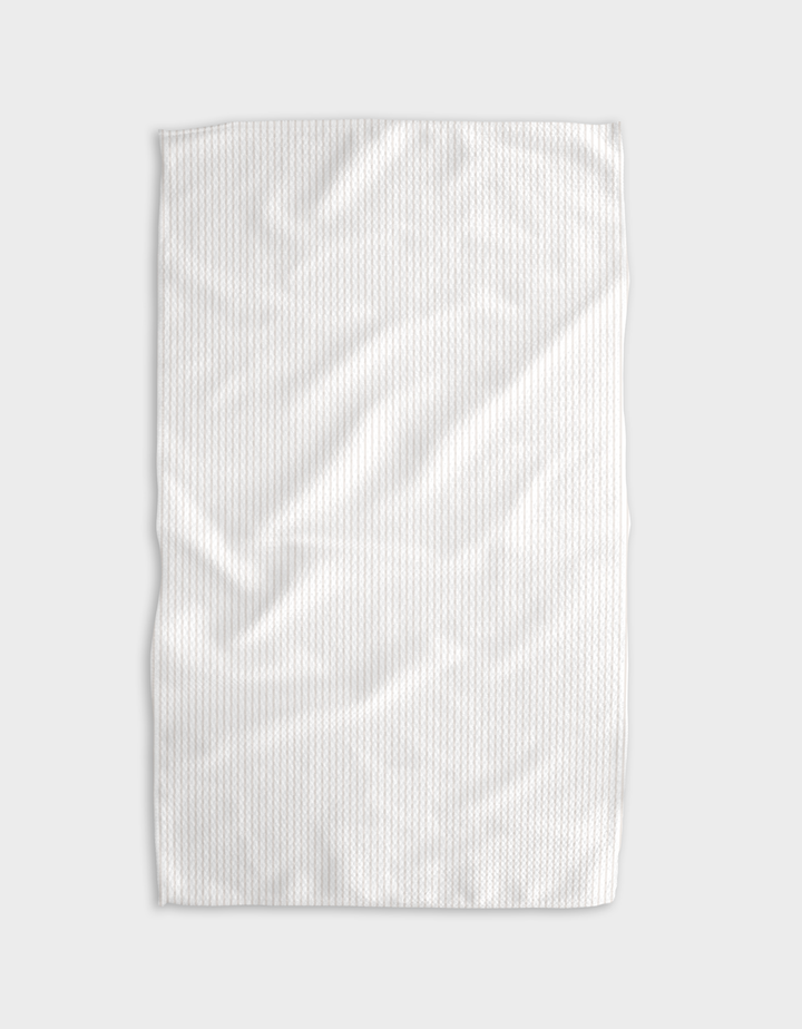 The Buy Guides Get In Line - Beige tea towel, crafted from Geoweave fabric with a subtle textured pattern, is laid flat on a light gray background, displaying slight folds and wrinkles.
