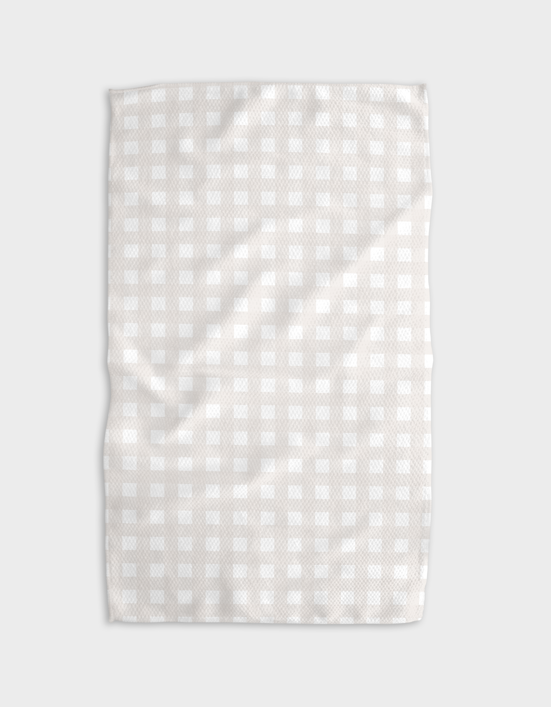 The Buy Guide’s Gigi - Beige tea towel, crafted from recycled materials, showcases a subtle checkered design on a soft, lightly wrinkled surface against a plain, light background.