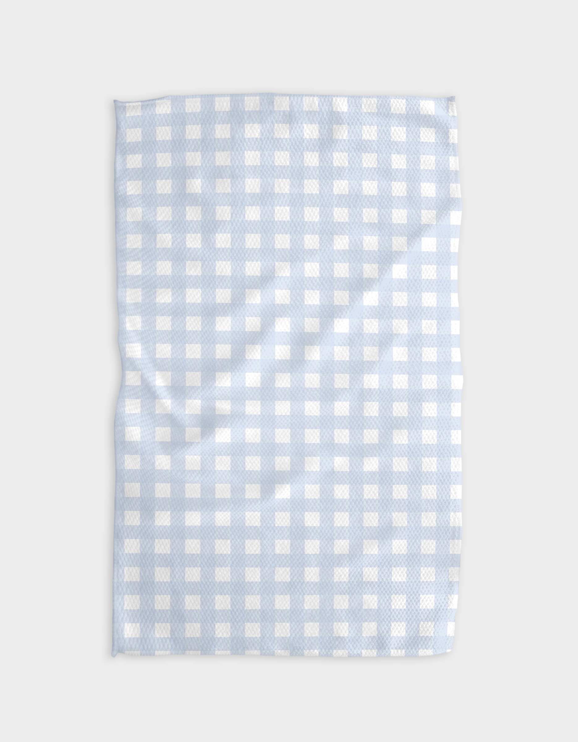 The Buy Guide’s Gigi - Light Blue tea towel features Geoweave™ fabric in a light blue and white check pattern, shown here lying flat with slight wrinkles on a plain light gray background.