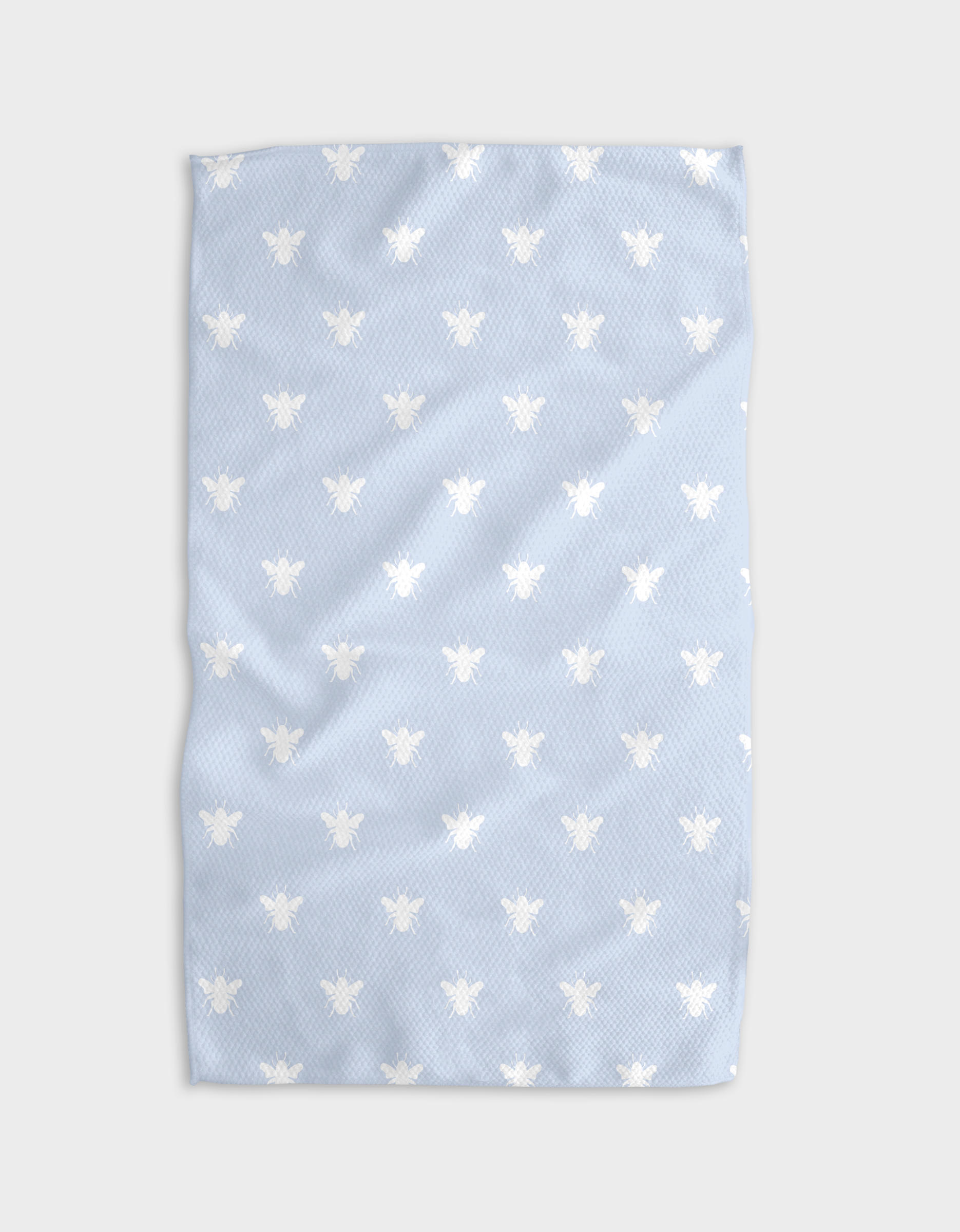 The Buy Guide’s Queen Bee - Light Blue towel features ultra-absorbent Geoweave fabric with evenly spaced white bees on a light blue background, shown slightly wrinkled against a plain light backdrop.