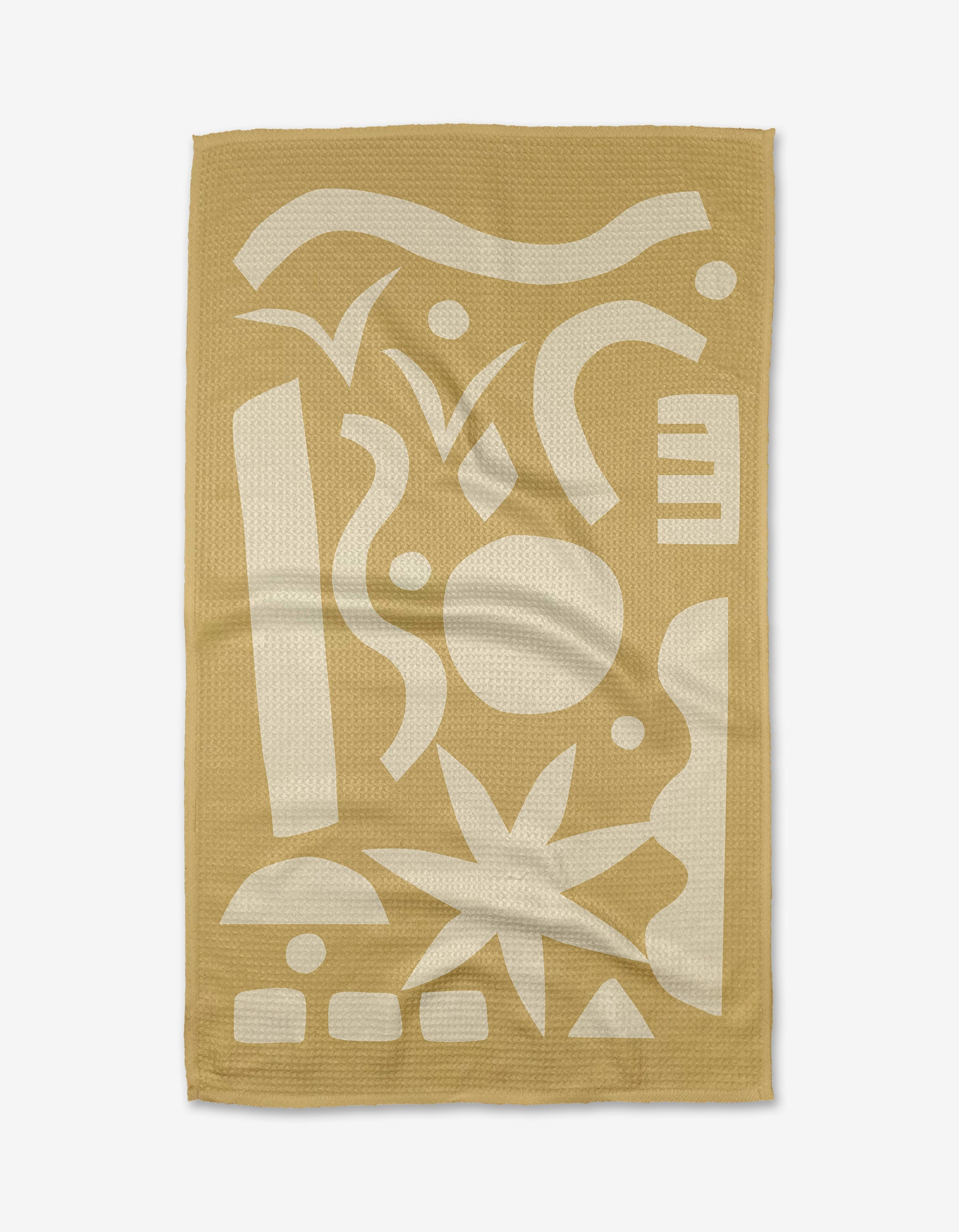 The Beach Walk tea towel by Elizabeth Edwards features a tan rectangular design with abstract white geometric shapes. Made from recycled materials, it has a subtle textured weave and a gently wrinkled look.