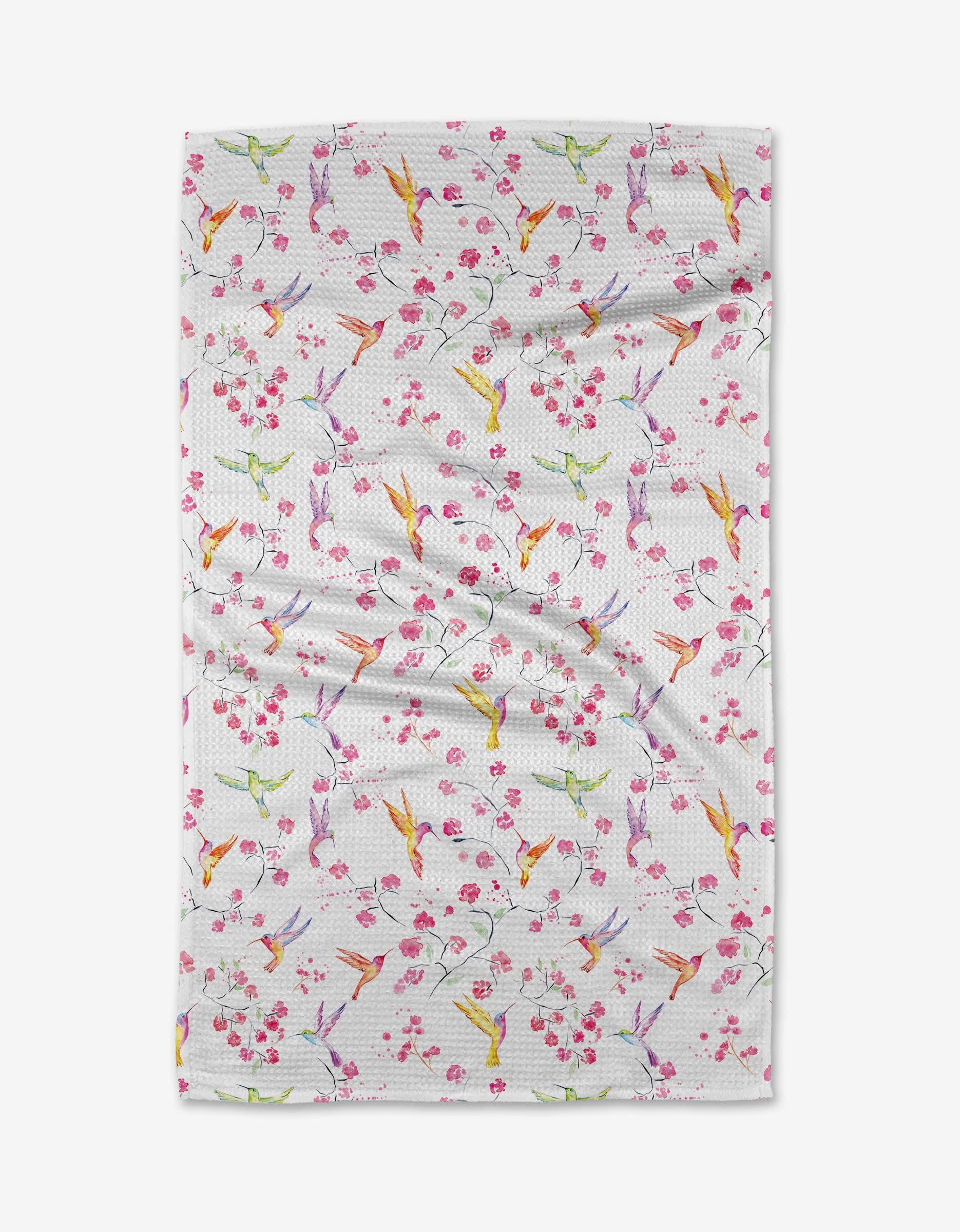 The Birds and Blooms tea towel by Elena Fay features a colorful pattern of hummingbirds and pink cherry blossoms on white Geoweave fabric with a subtle dotted texture.