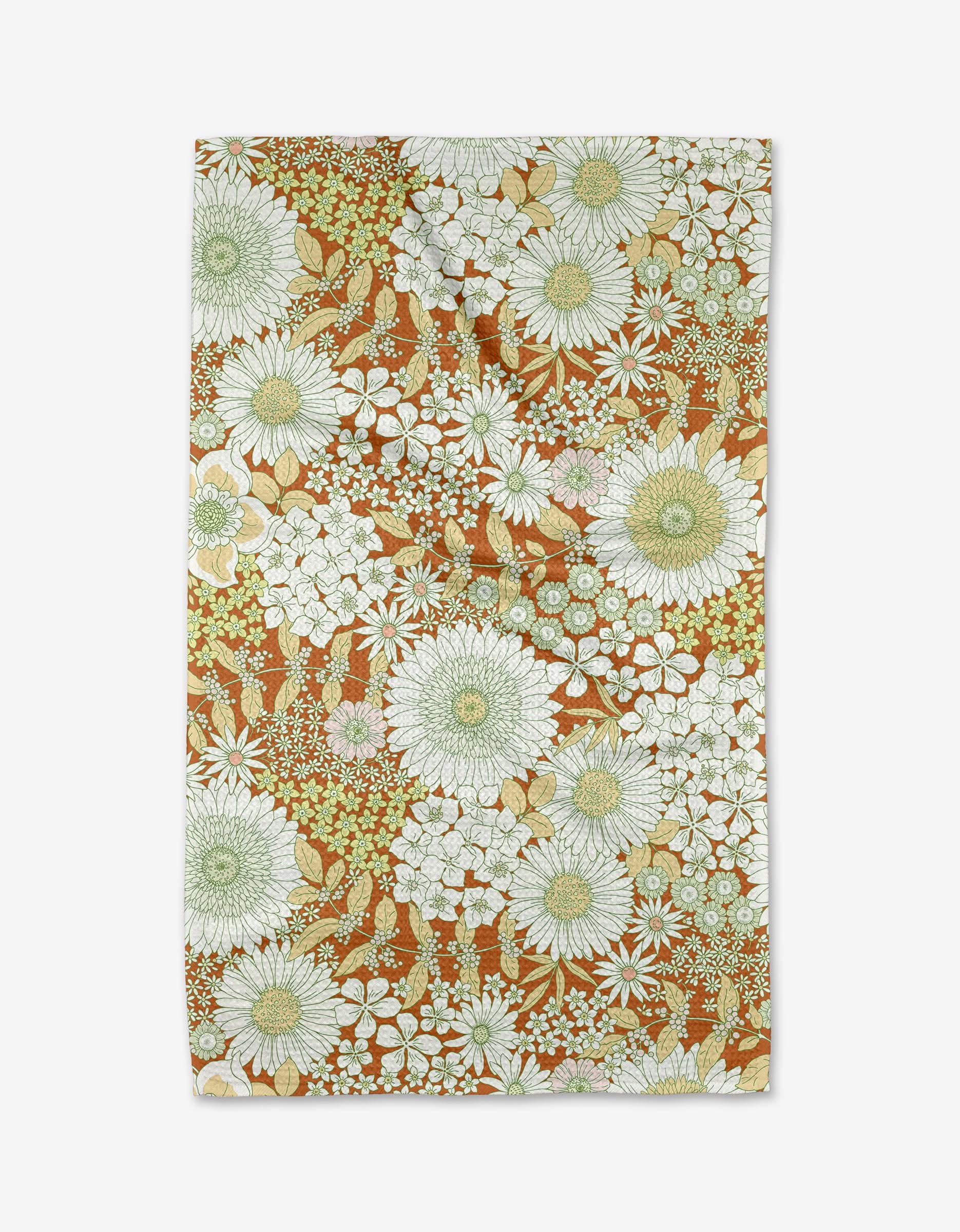 The Dabney Lee Botanical Garden tea towel is made from Geoweave fabric and showcases a dense floral design with white and light green flowers, small blossom clusters, and green leaves on a brown background.