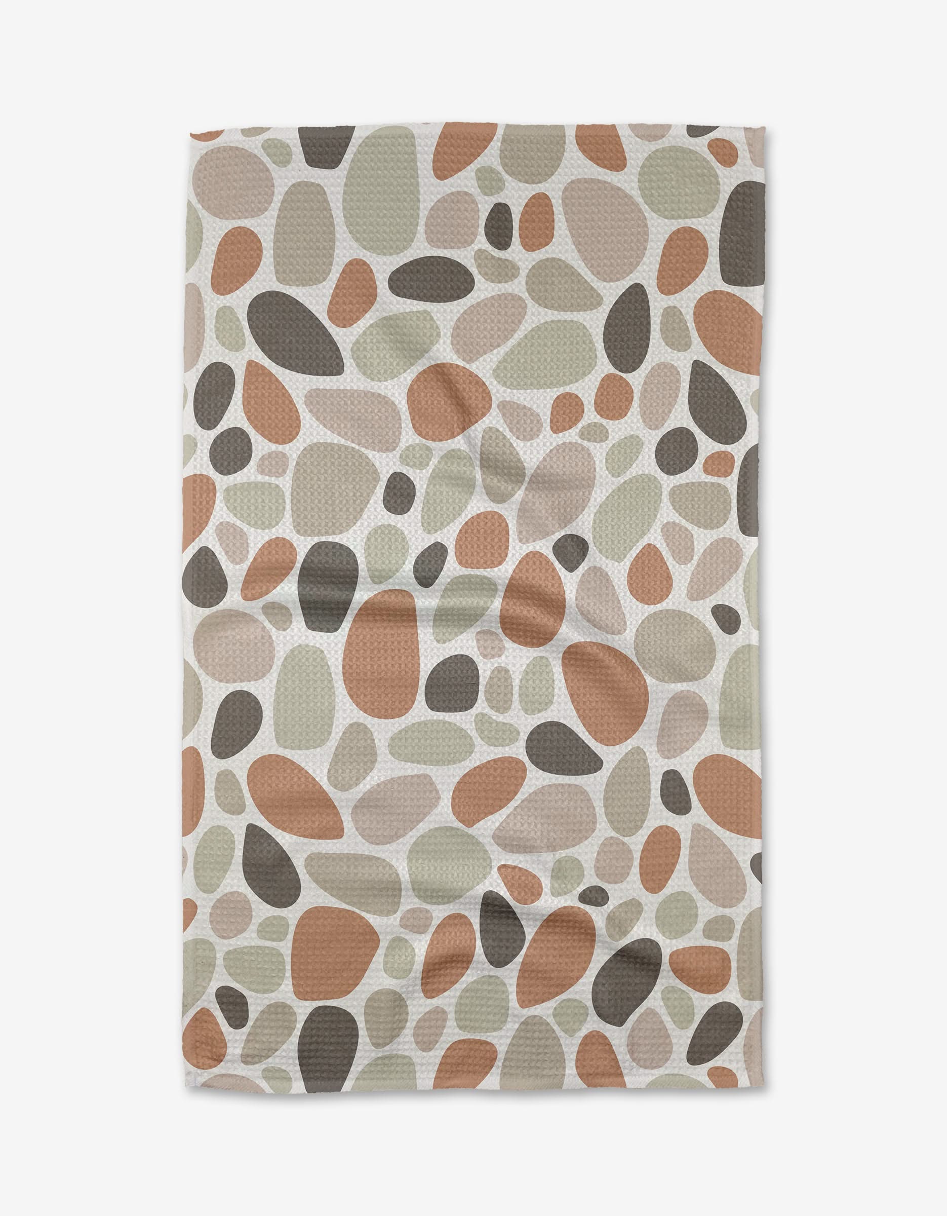 Cactus Pieces by Rosa Kichline is a rectangular fabric with an abstract pebble pattern in brown, beige, and olive green on a cream background. Made from ultra-absorbent Geoweave fabric, its surface has a slightly wrinkled look.