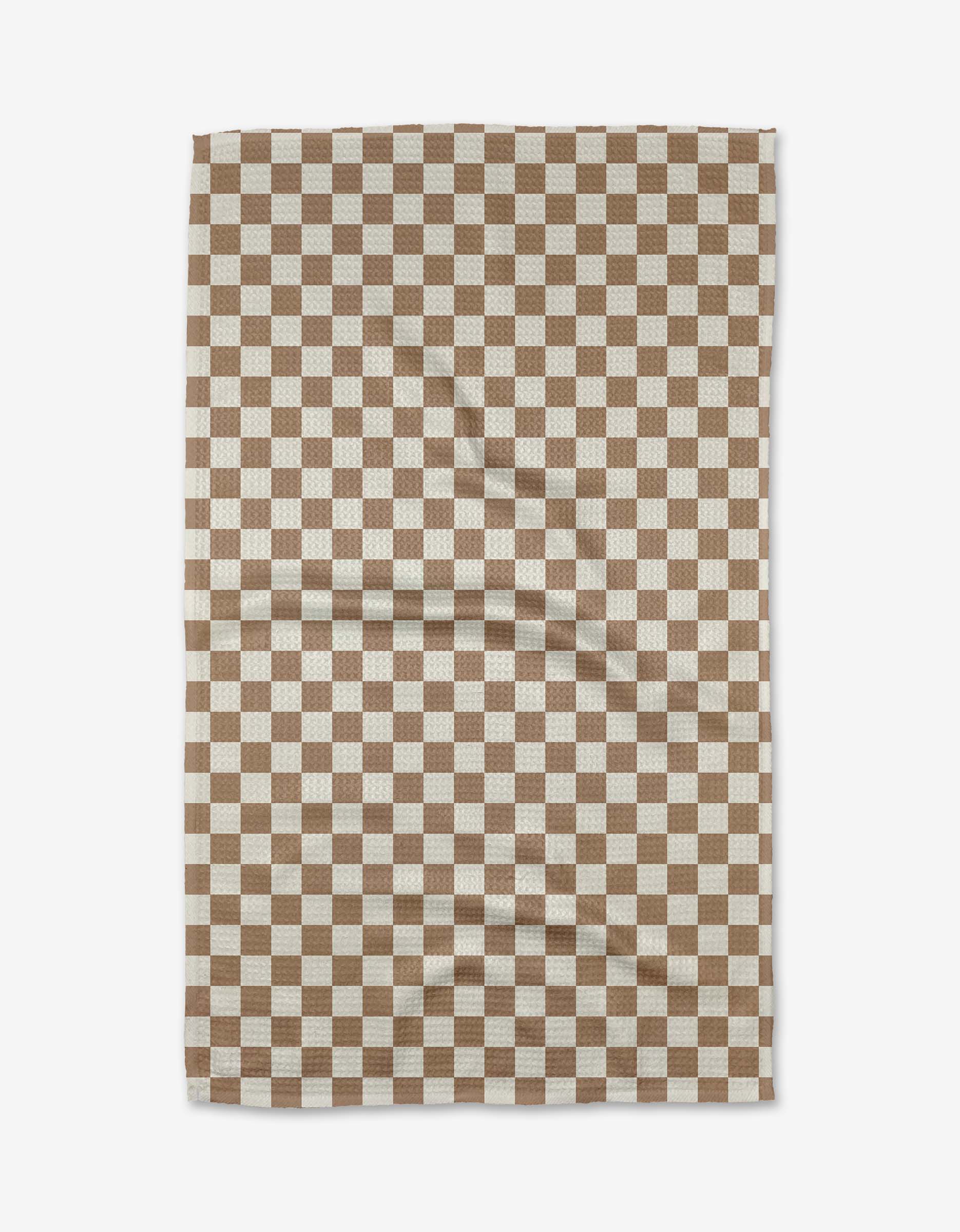 The Kelsi Fullmer Check Mate is a rectangular cloth crafted from ultra-absorbent Geoweave fabric, featuring a brown and white checkered grid pattern with subtle creases visible when laid flat.