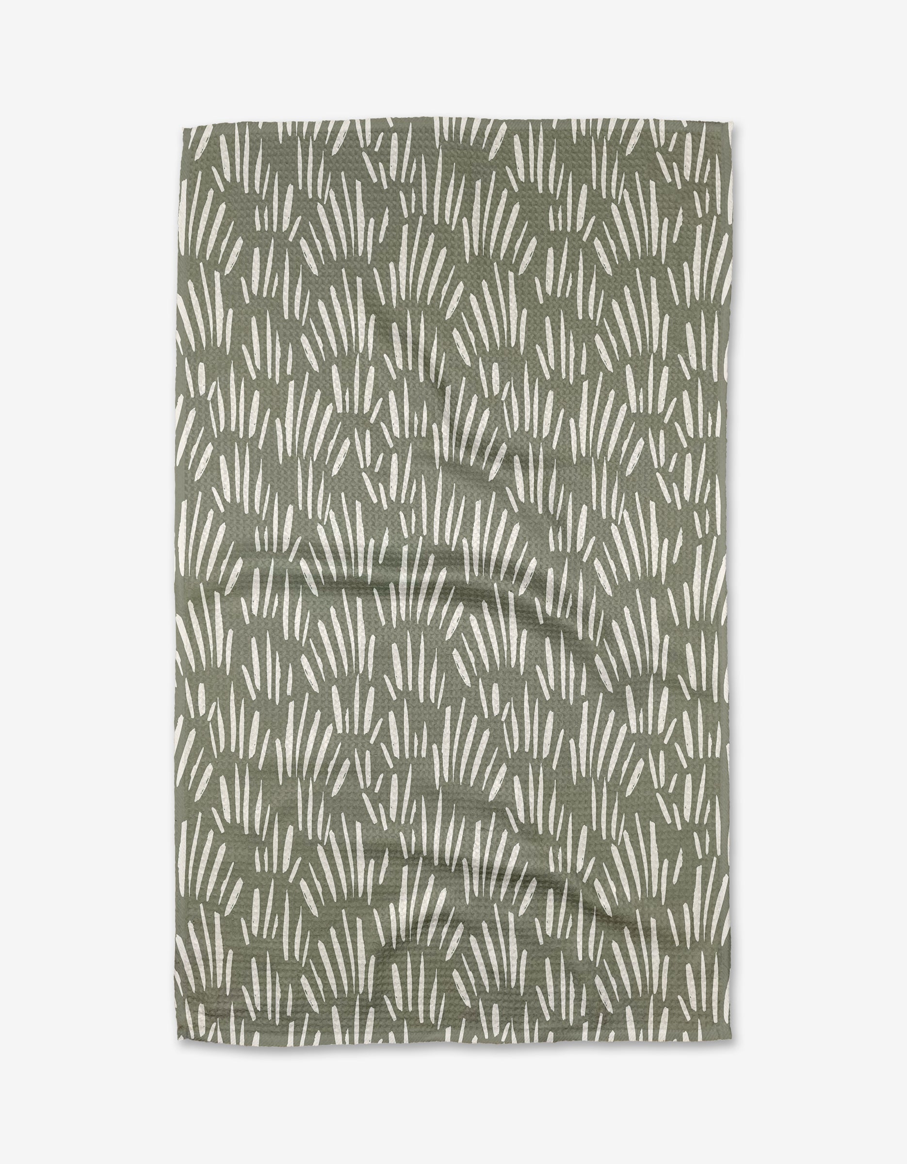 The Country Fields tea towel by Hufton Studio is made from green Geoweave fabric with a repeating pattern of white, curved lines resembling abstract grass or leaves. The towel is shown laid flat with slight wrinkles visible.